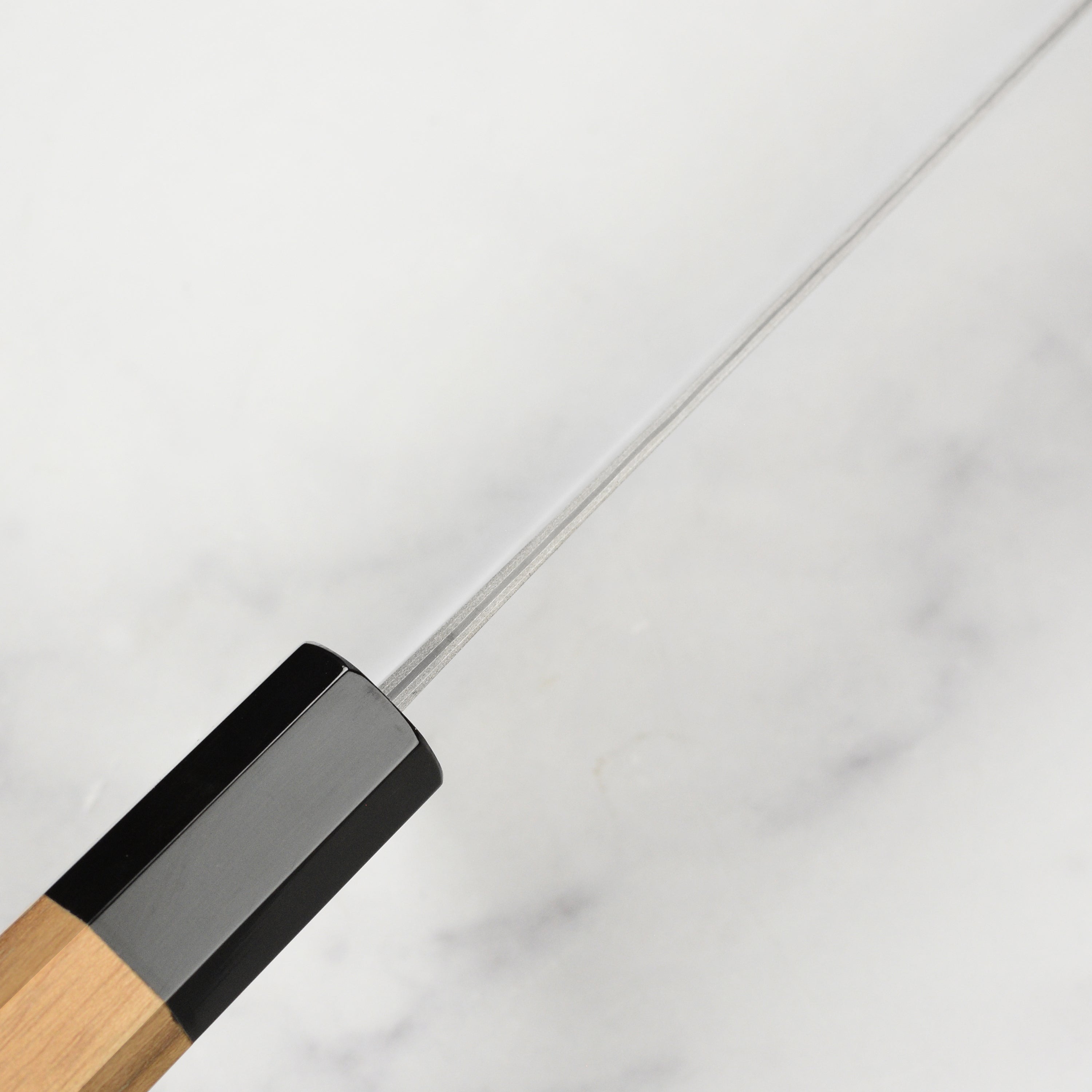 The Shiro Kamo knife displayed next to fresh ingredients, emphasizing its premium quality.