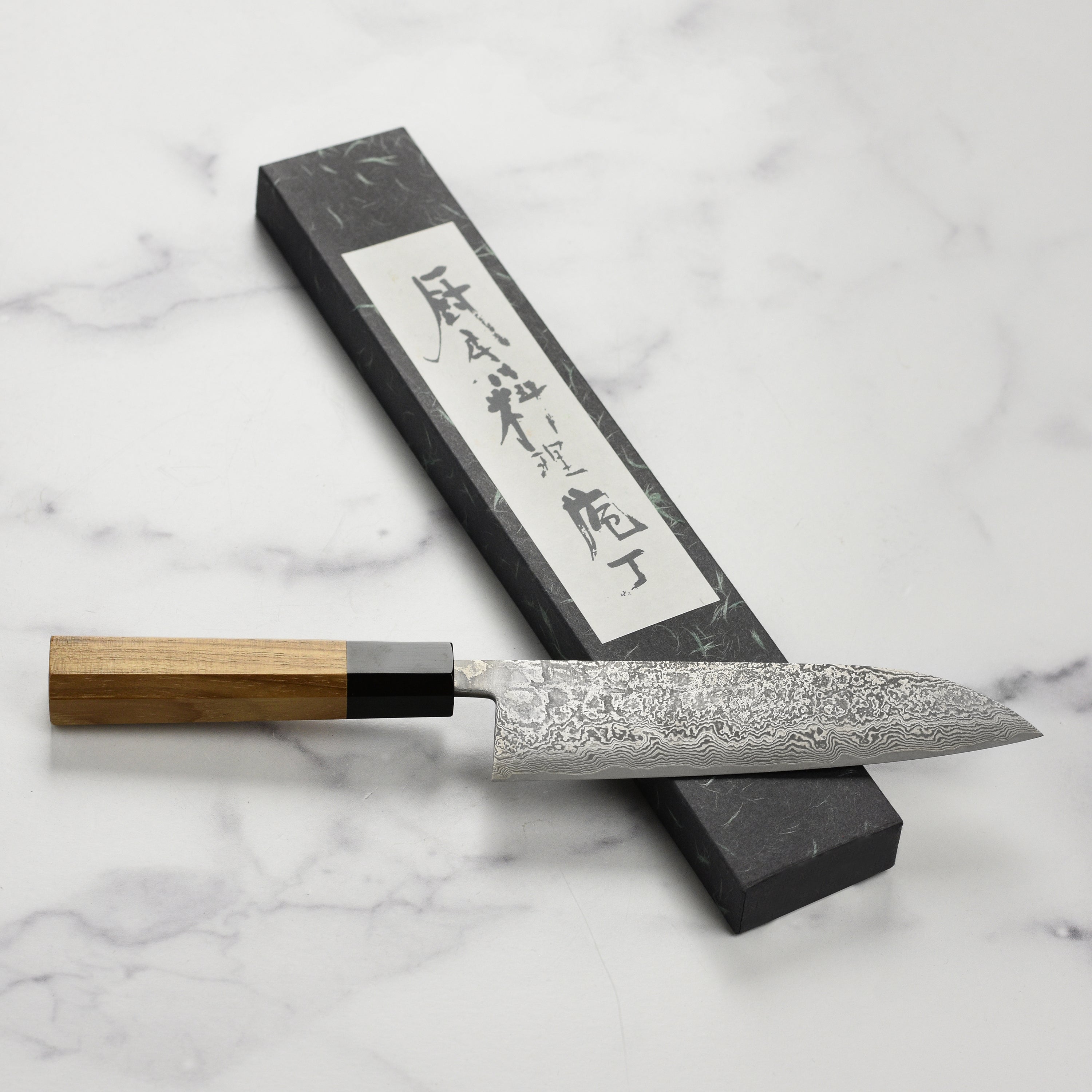 The Shiro Kamo knife displayed next to fresh ingredients, emphasizing its premium quality.