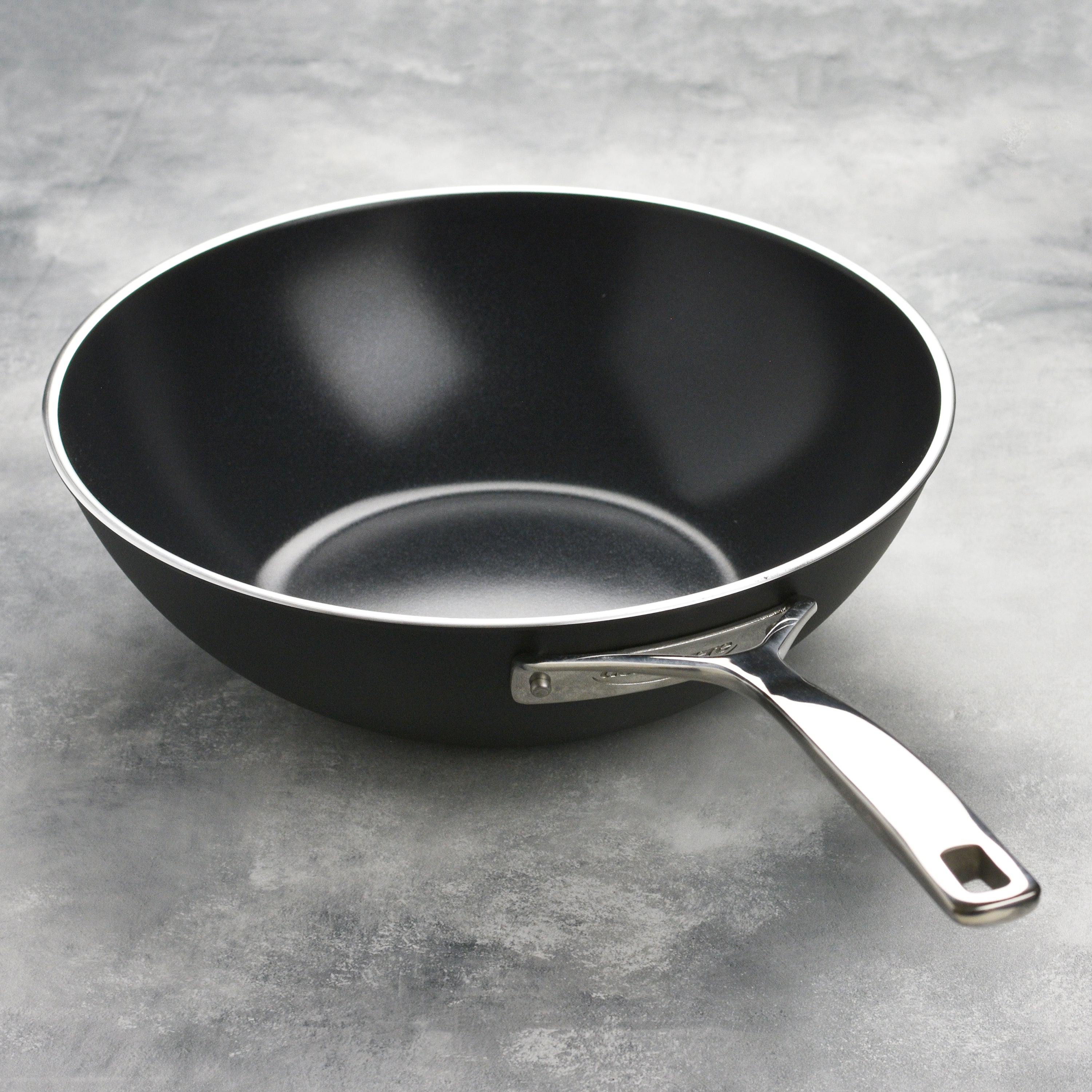 Side angle of ceramic wok with stainless steel handles and flared rim for easy pouring
