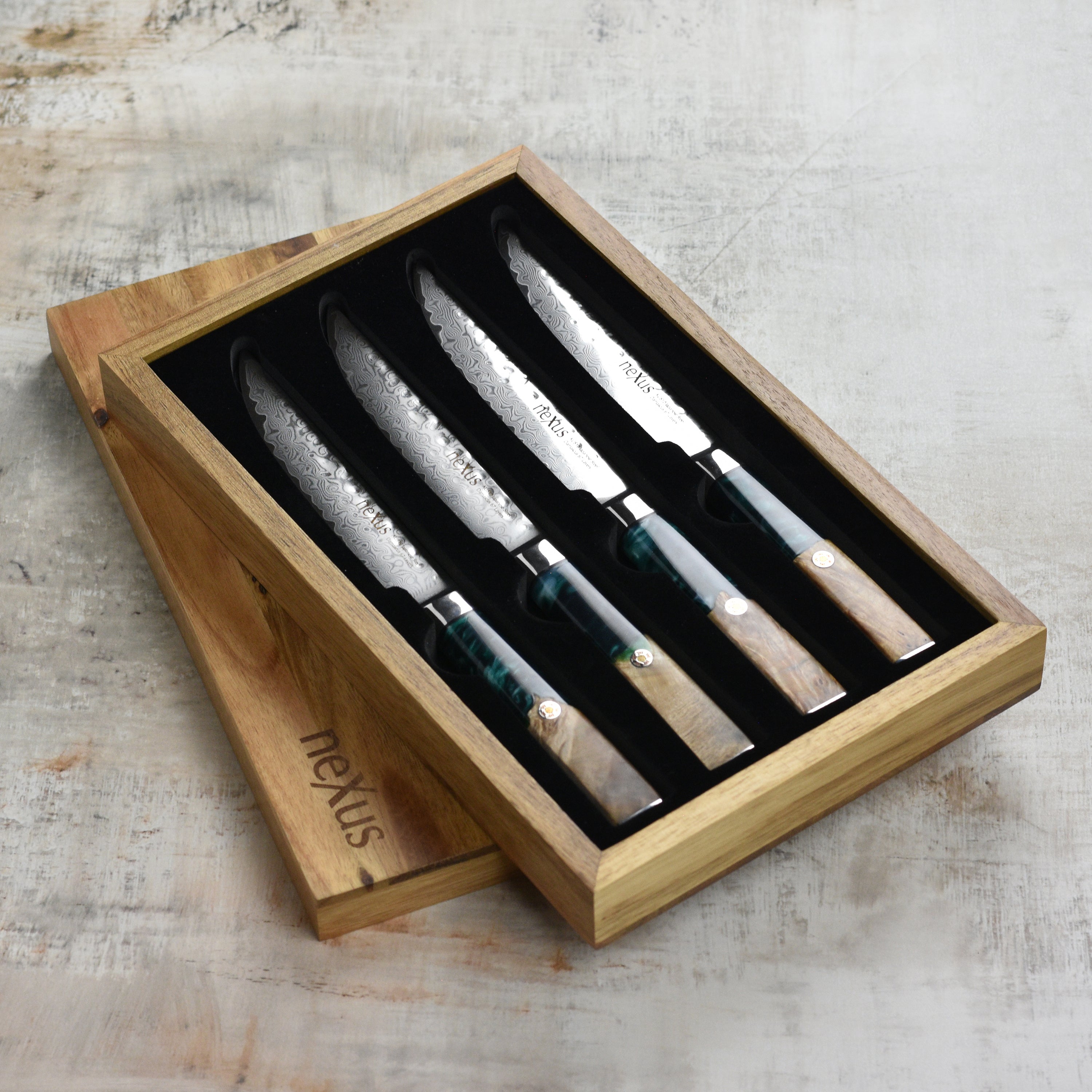 Damascus steak knives with ocean blue resin and wooden handles on a dining table