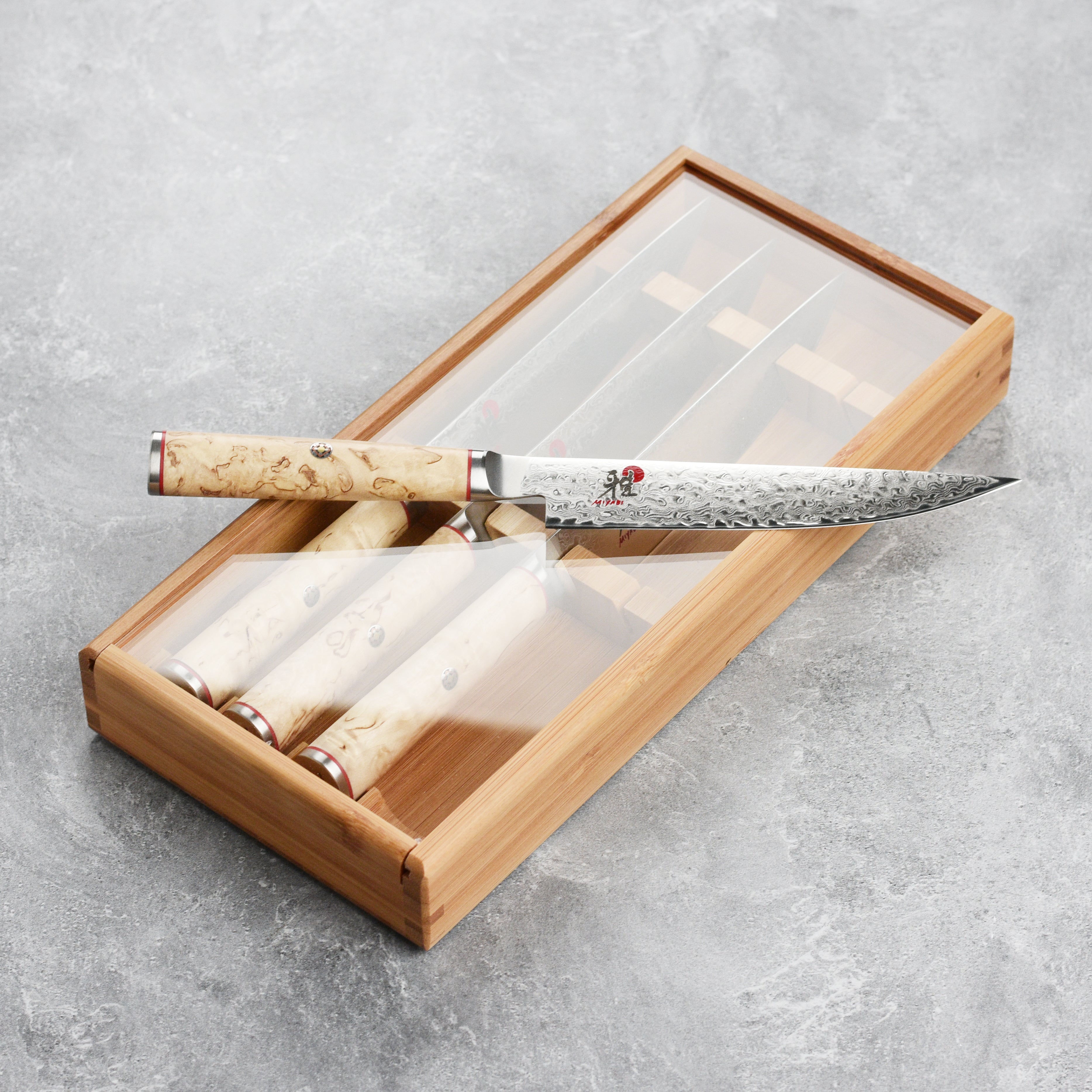 Close-up of Miyabi Damascus steel blade with katana edge against a wooden cutting board
