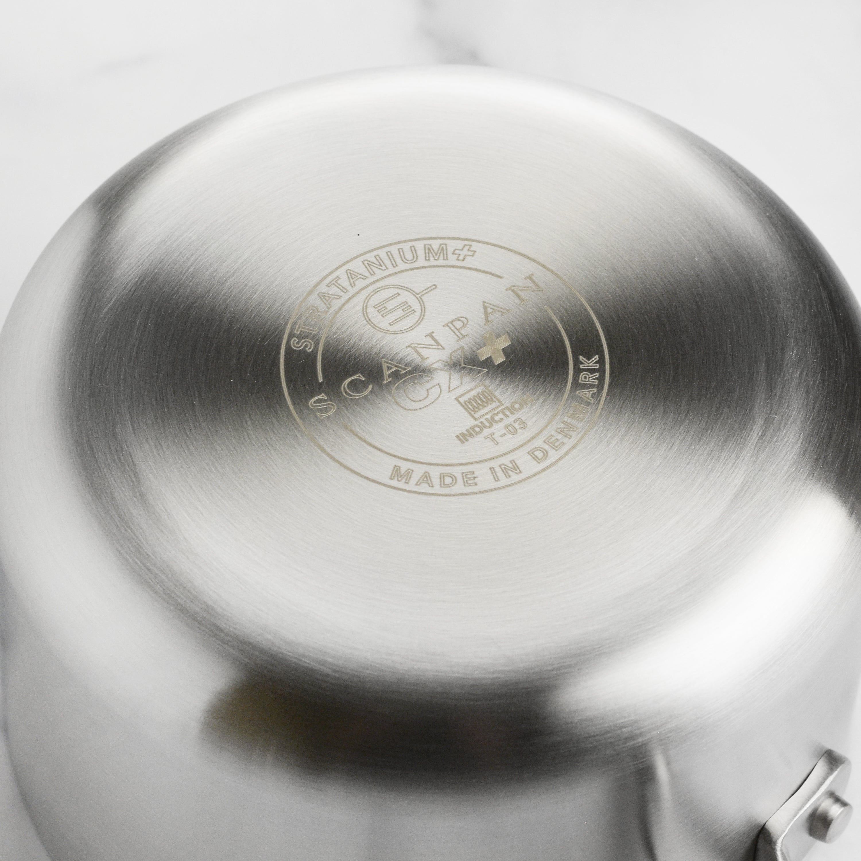 A chef using the Scanpan CX+ nonstick saucepan to prepare a sauce, showcasing its induction-ready capabilities.