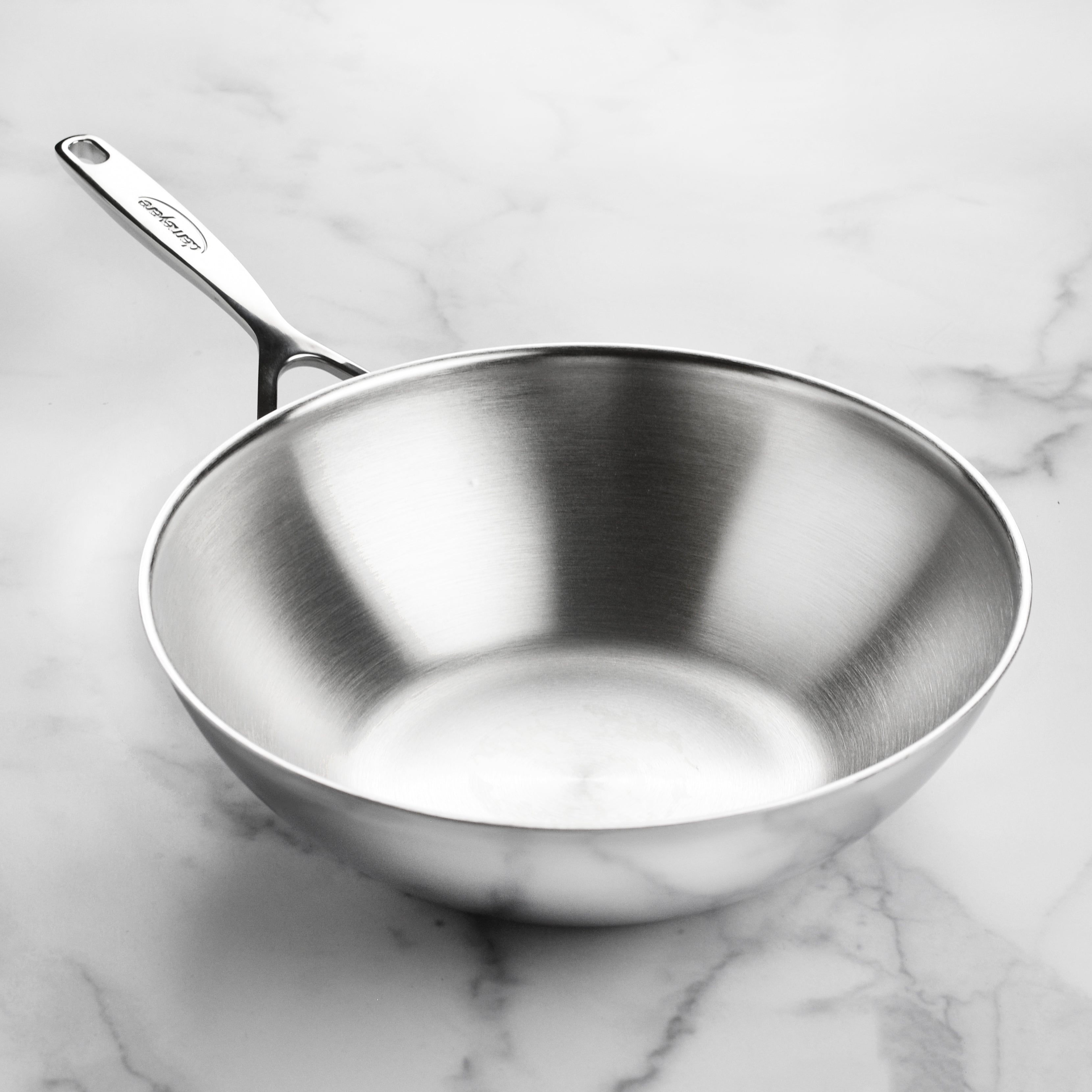 Stainless steel wok in use on an induction cooktop with vegetables inside