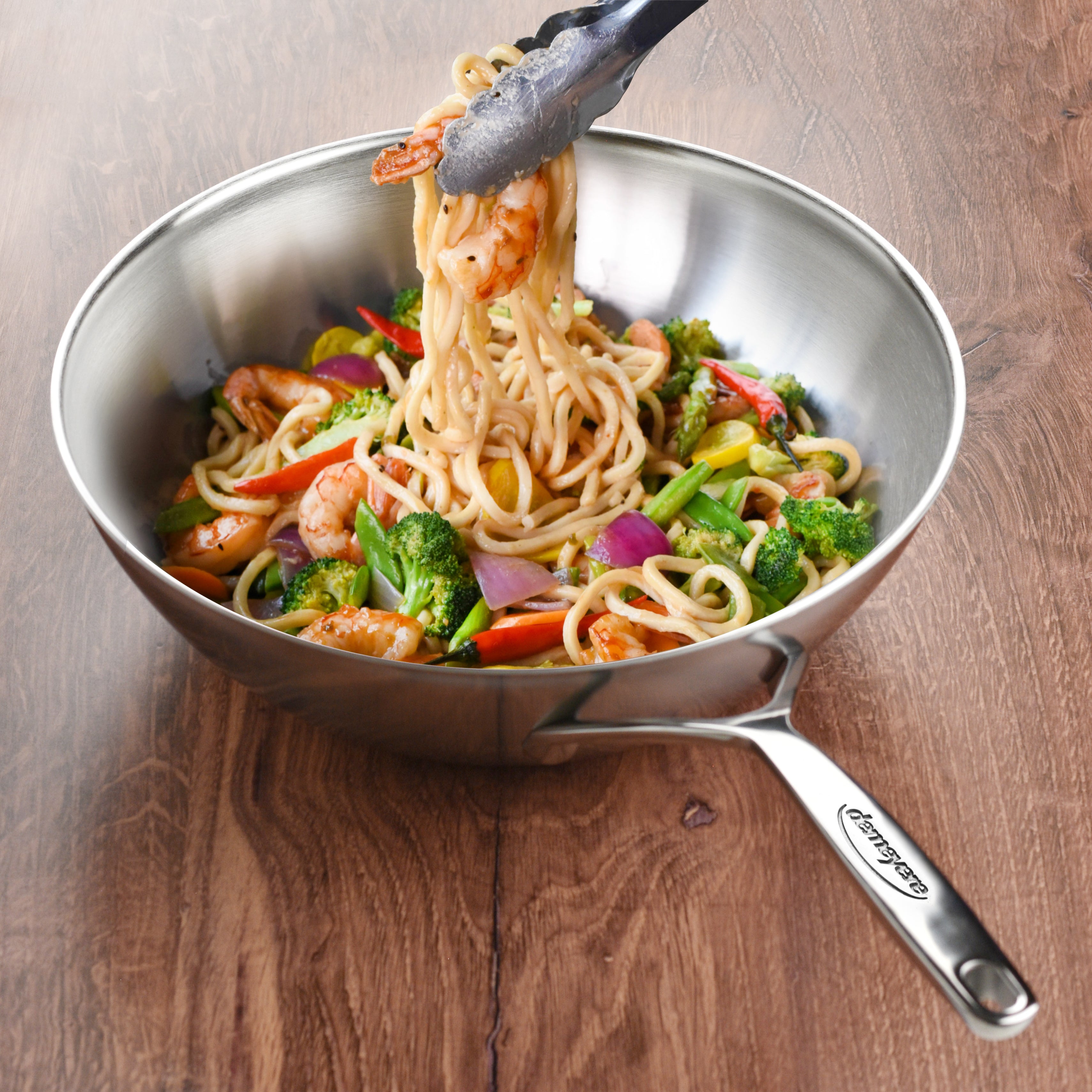 Stainless steel wok in use on an induction cooktop with vegetables inside