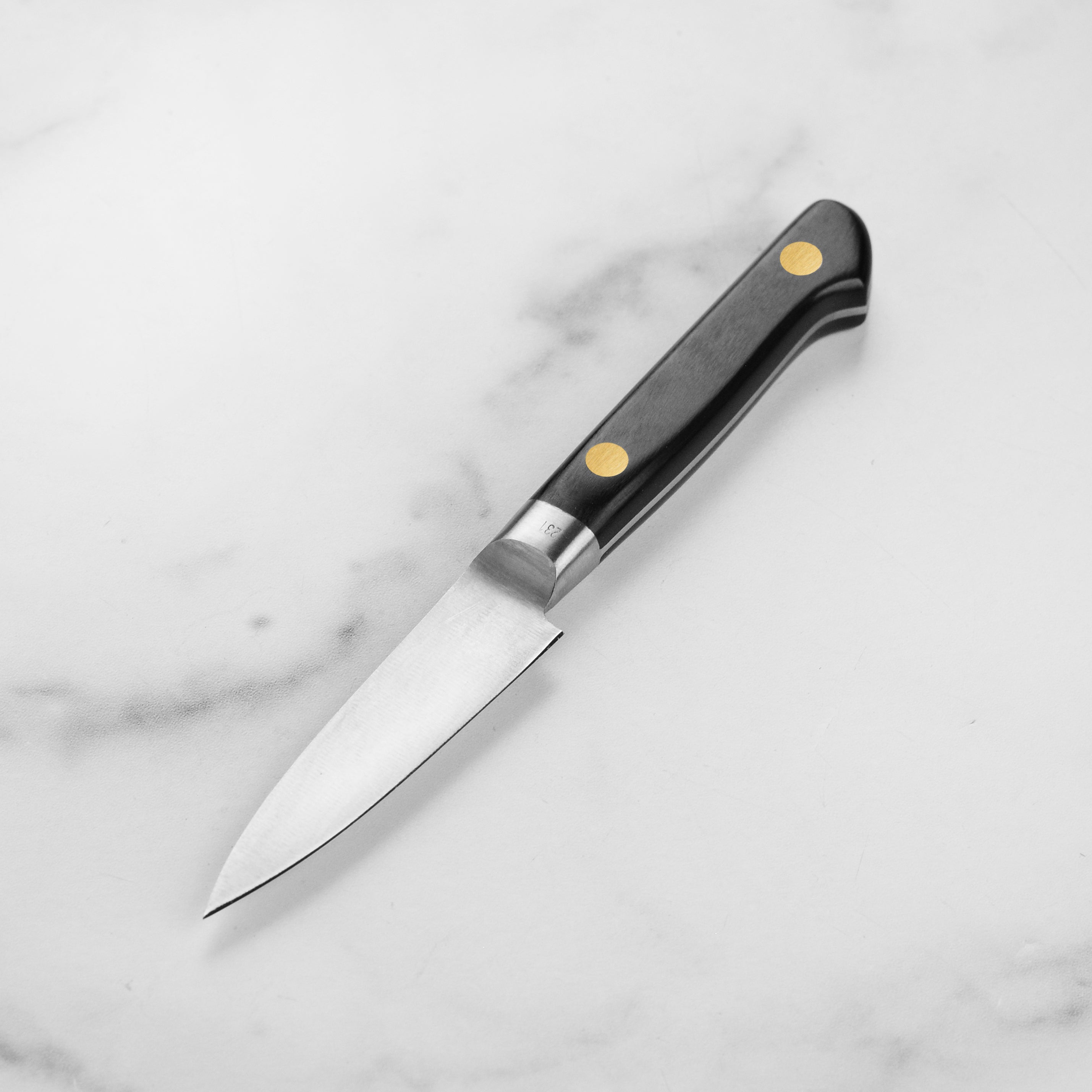 Close-up view of the hand-forged blade of the Misono petty knife highlighting its sharpness and craftsmanship.