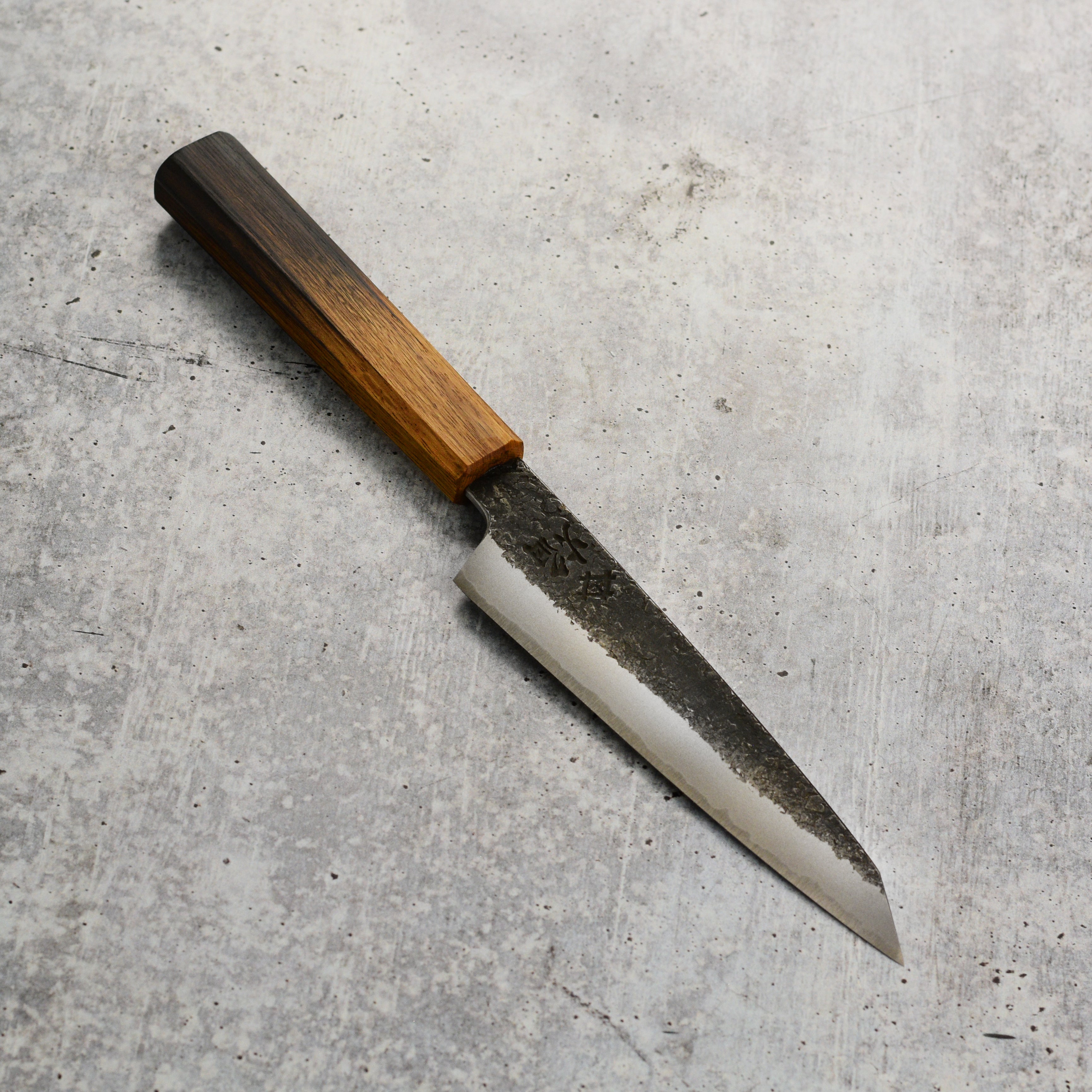Close-up of the hand-forged Japanese chef knife with a rustic hammered finish.