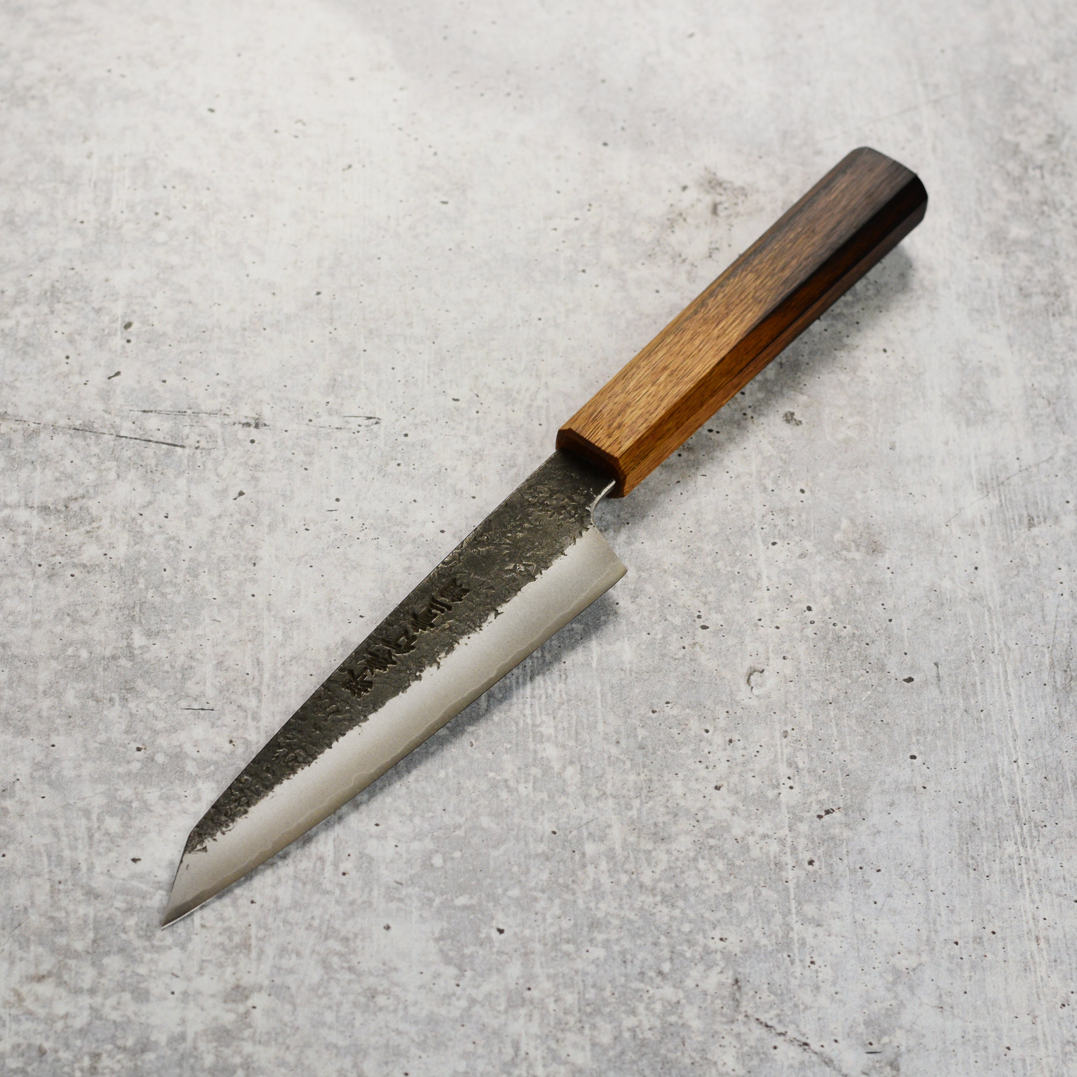 The ergonomic burnt oak handle of the Japanese chef knife, designed for comfort.