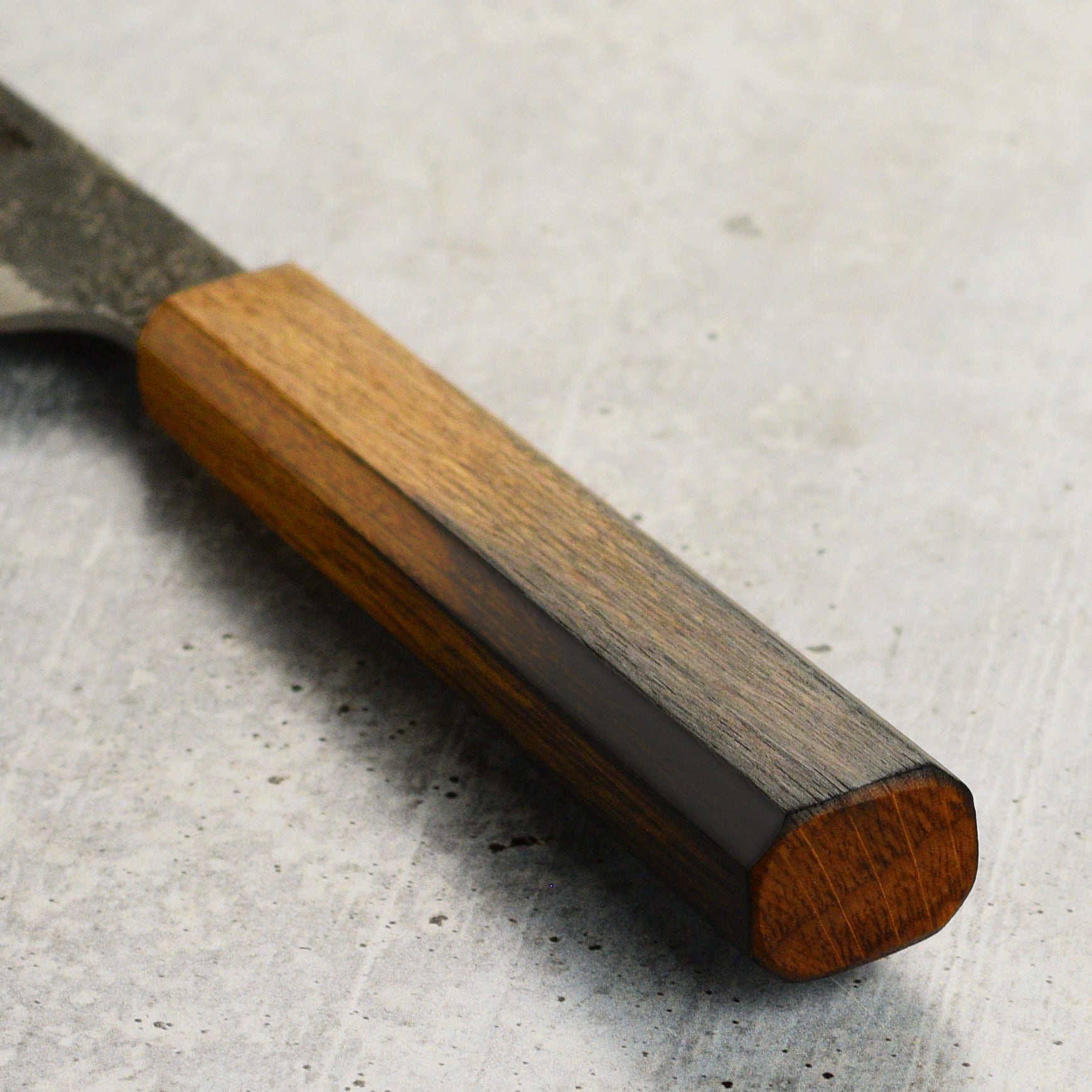 The ergonomic burnt oak handle of the Japanese chef knife, designed for comfort.