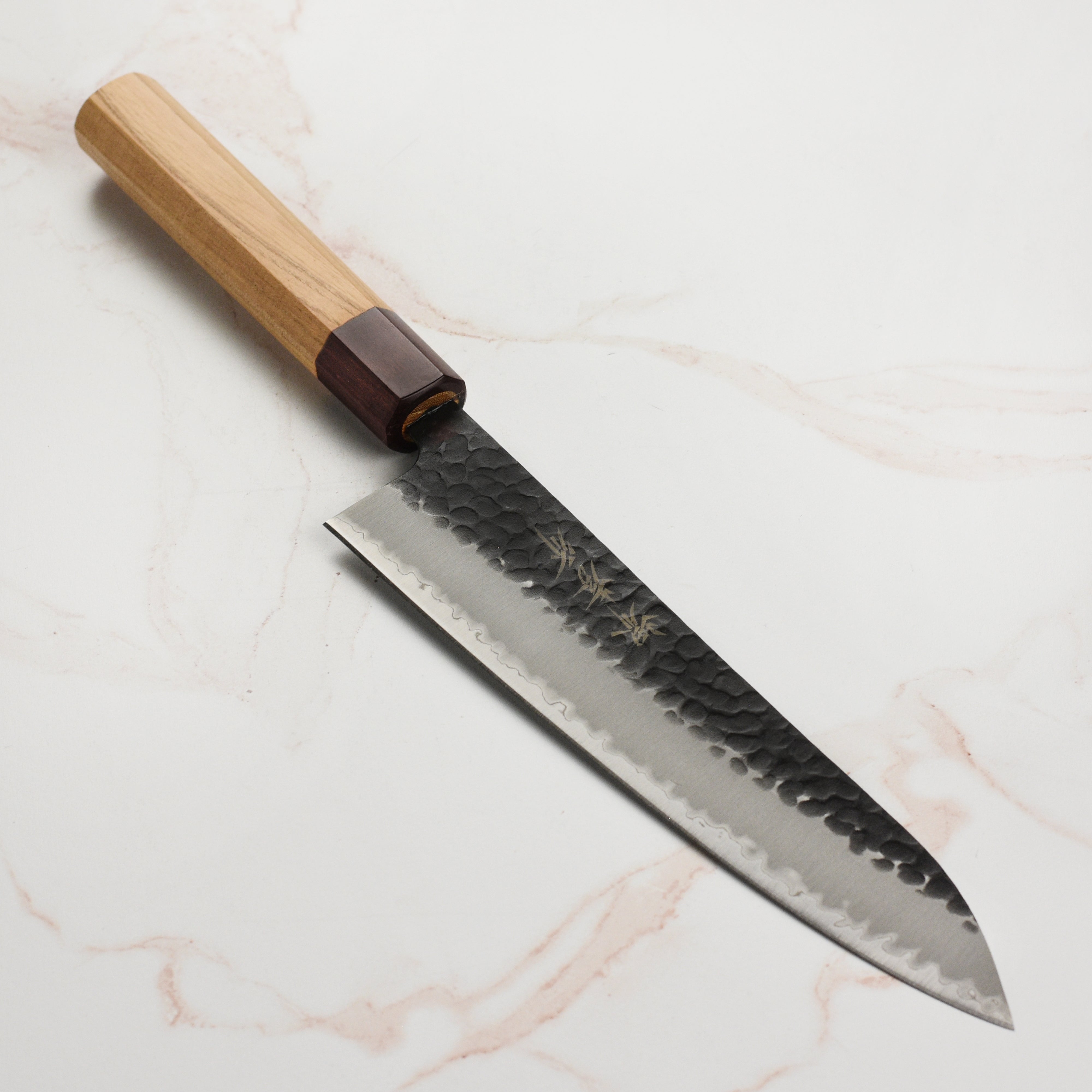 Takayuki Aogami Gyuto knife showcasing its blue carbon steel blade and wooden handle from a side angle.