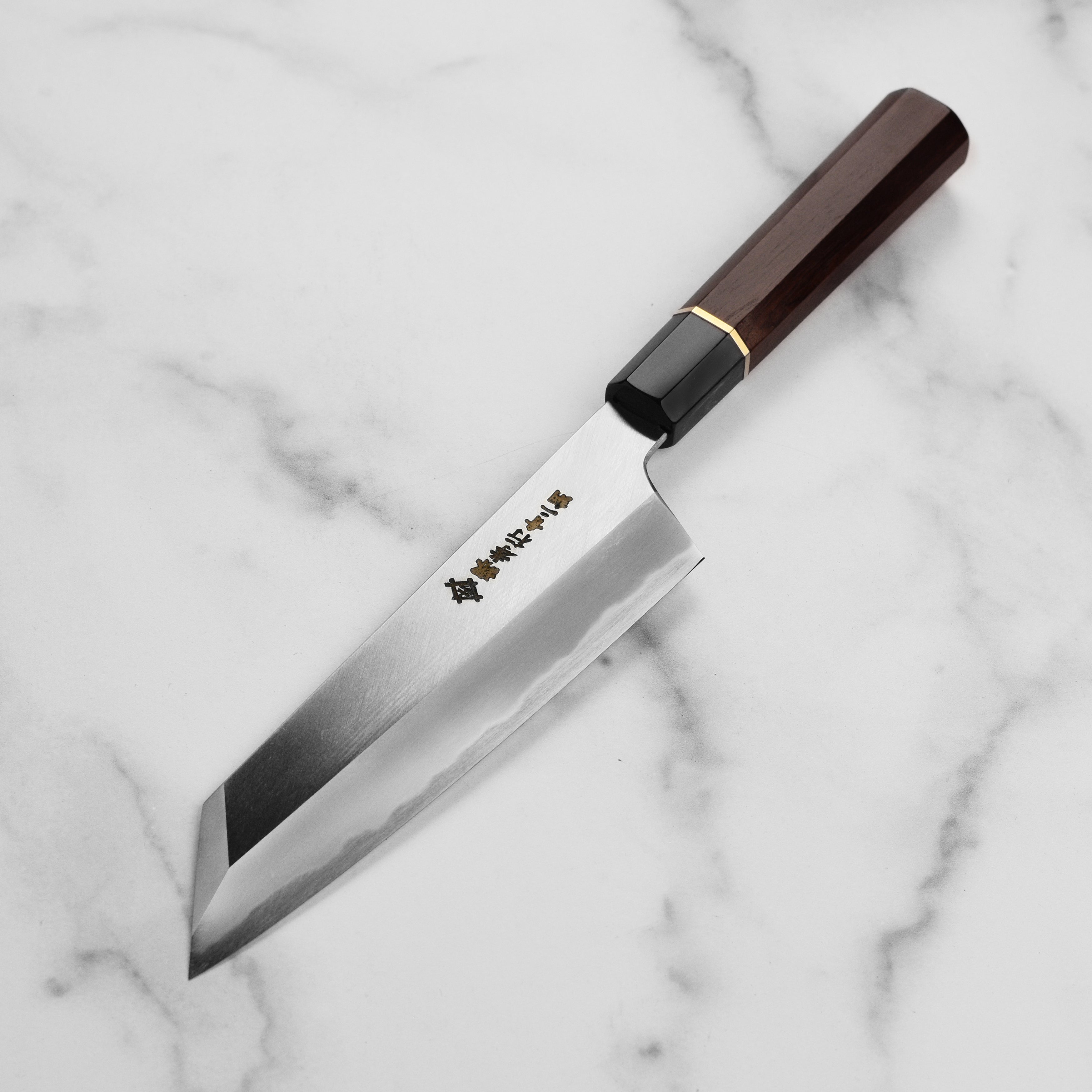 Takayuki Gyuto knife with saya displayed on a wooden cutting board, highlighting its craftsmanship.