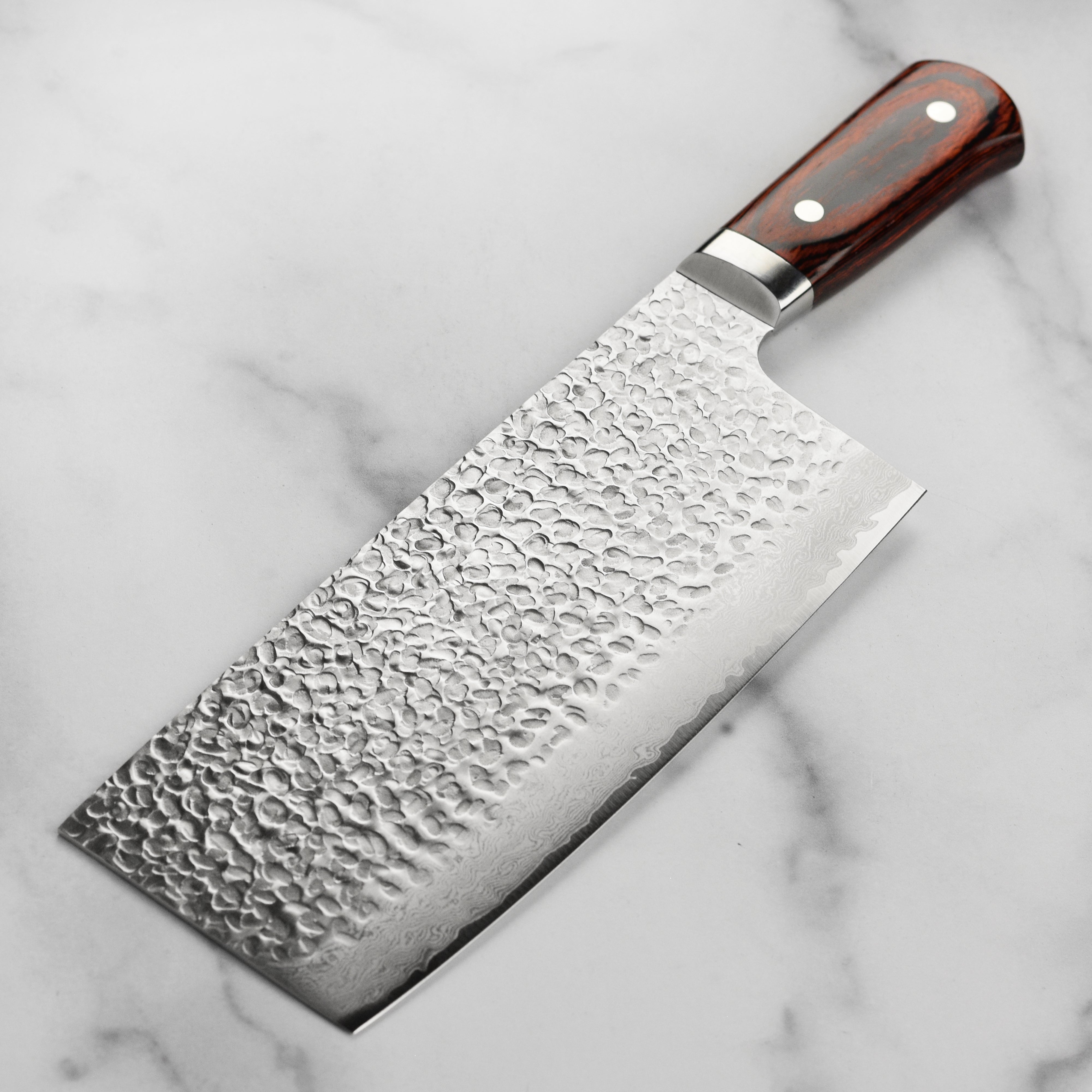 Sakai Hammered Damascus Chefs Knife in action, slicing through fresh vegetables.
