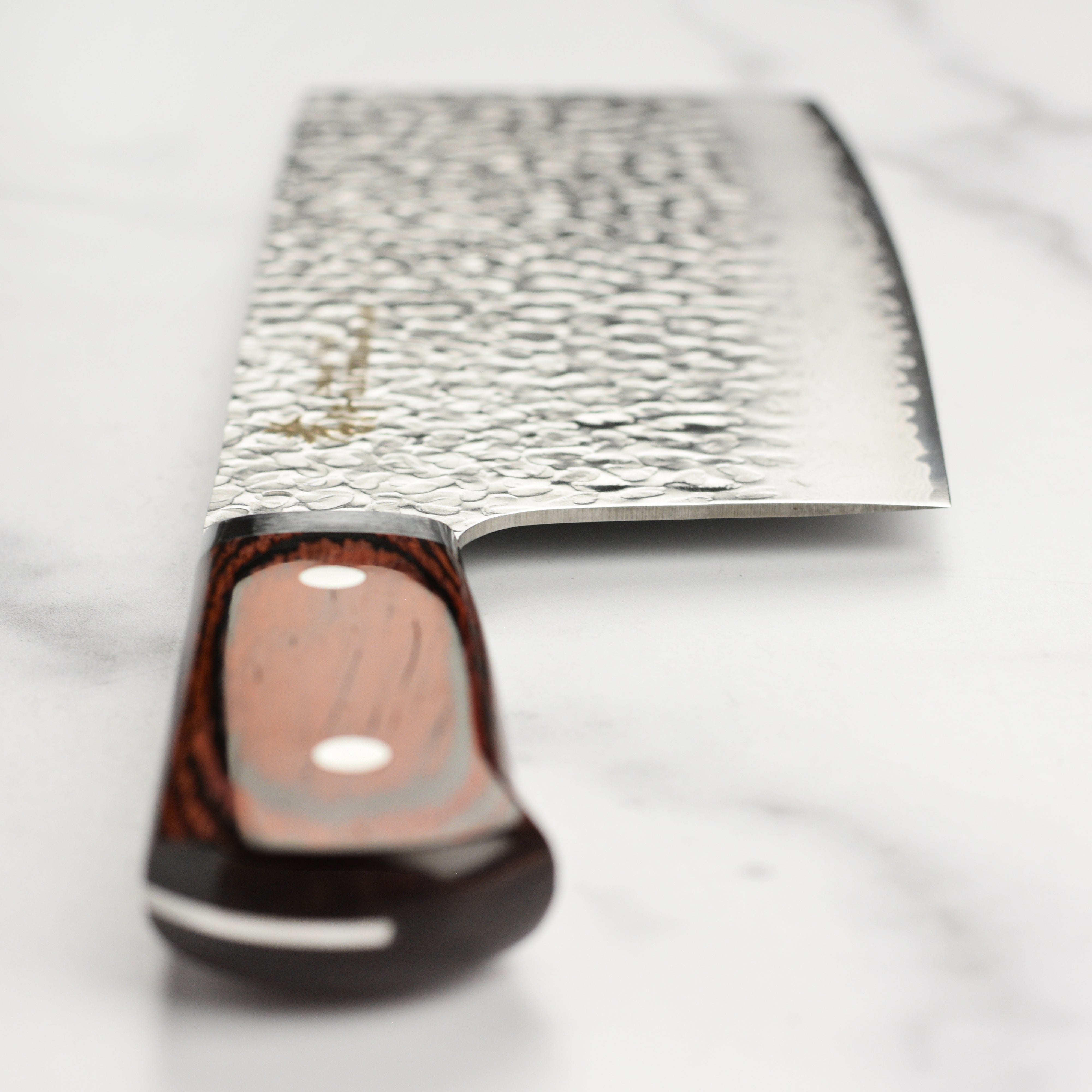 Sakai Hammered Damascus Chefs Knife in action, slicing through fresh vegetables.