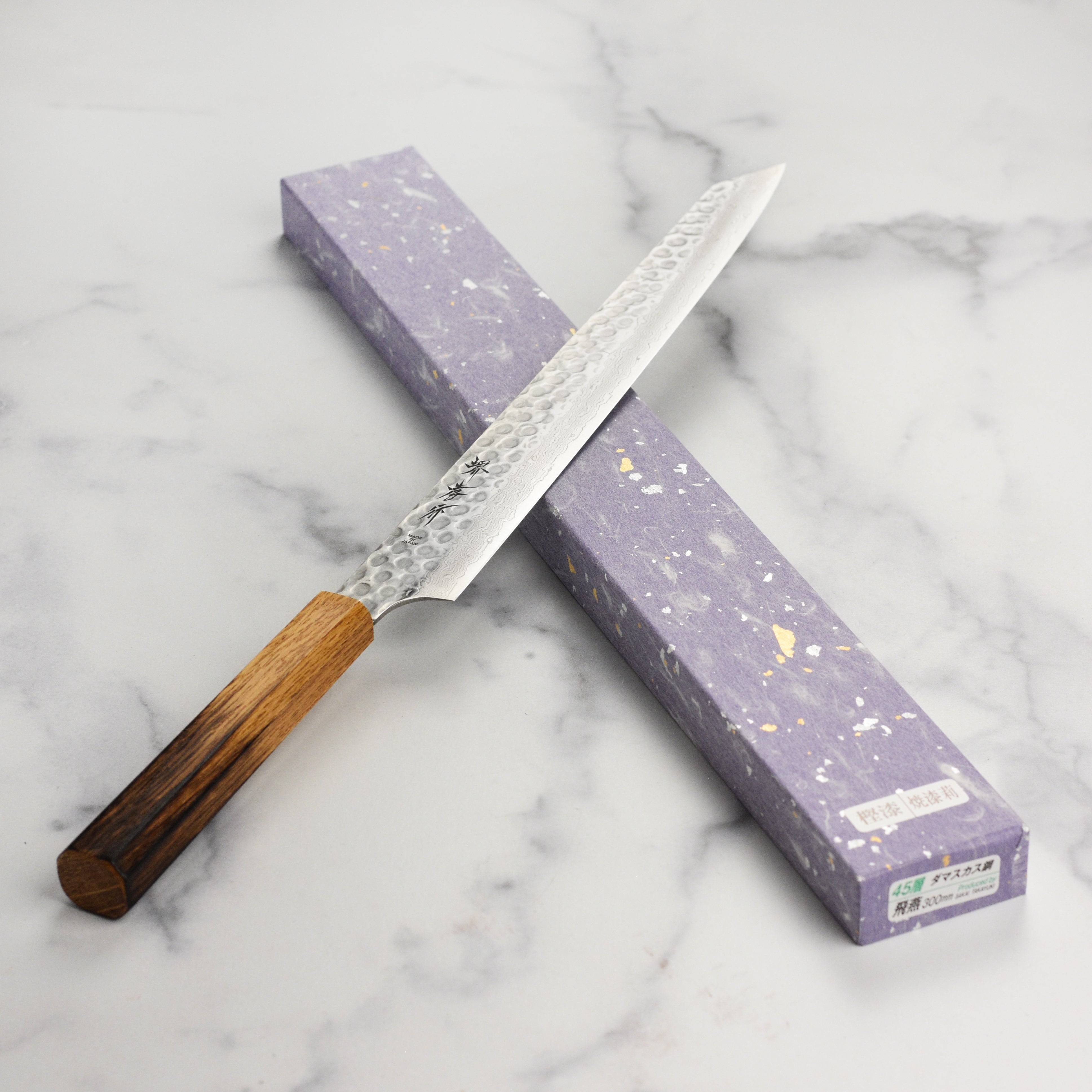 Sakai Tsuchime Damascus knife in action, slicing fresh sushi ingredients.