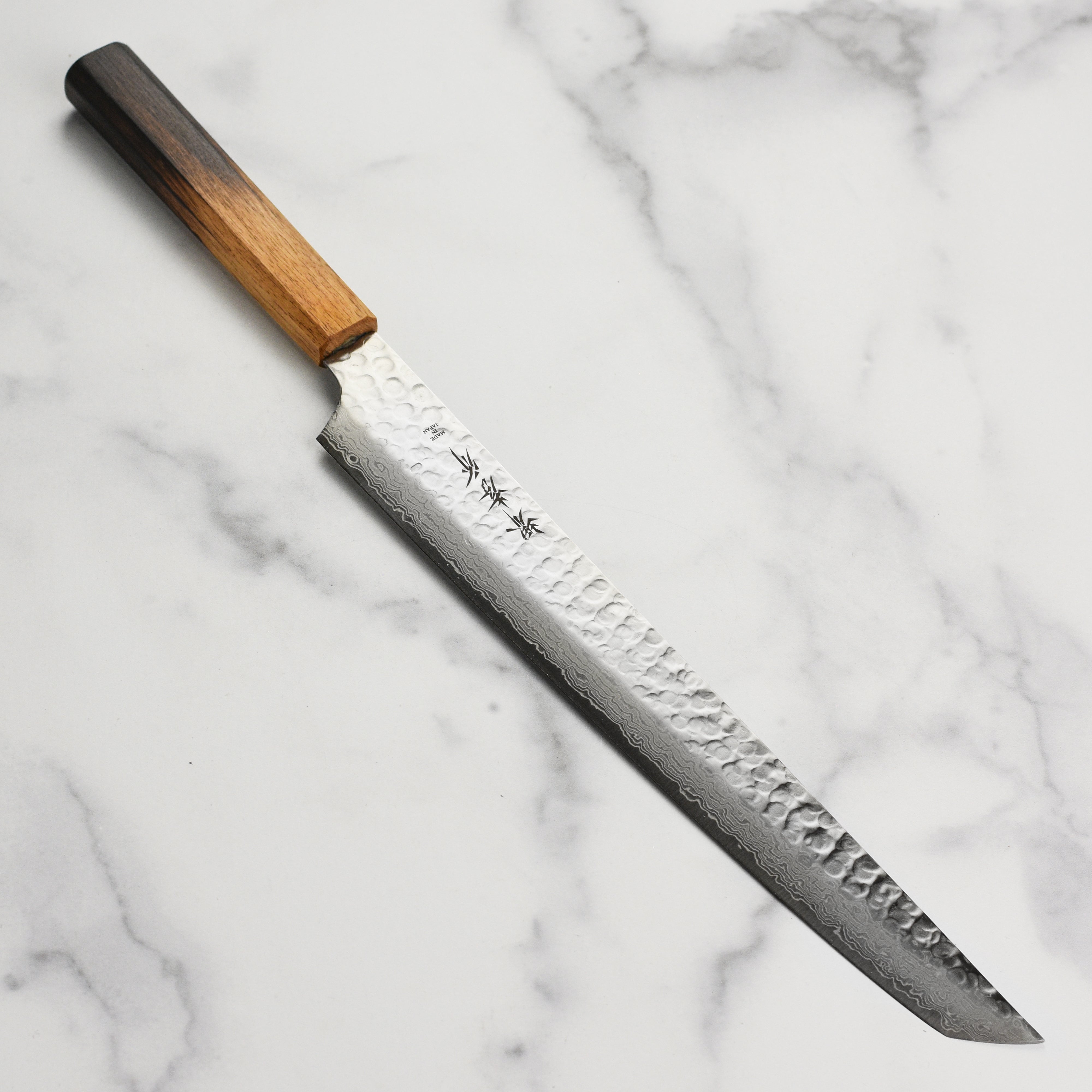 Close-up of the Premium Sakimaru-Yanagiba knife blade, highlighting the Damascus steel pattern.
