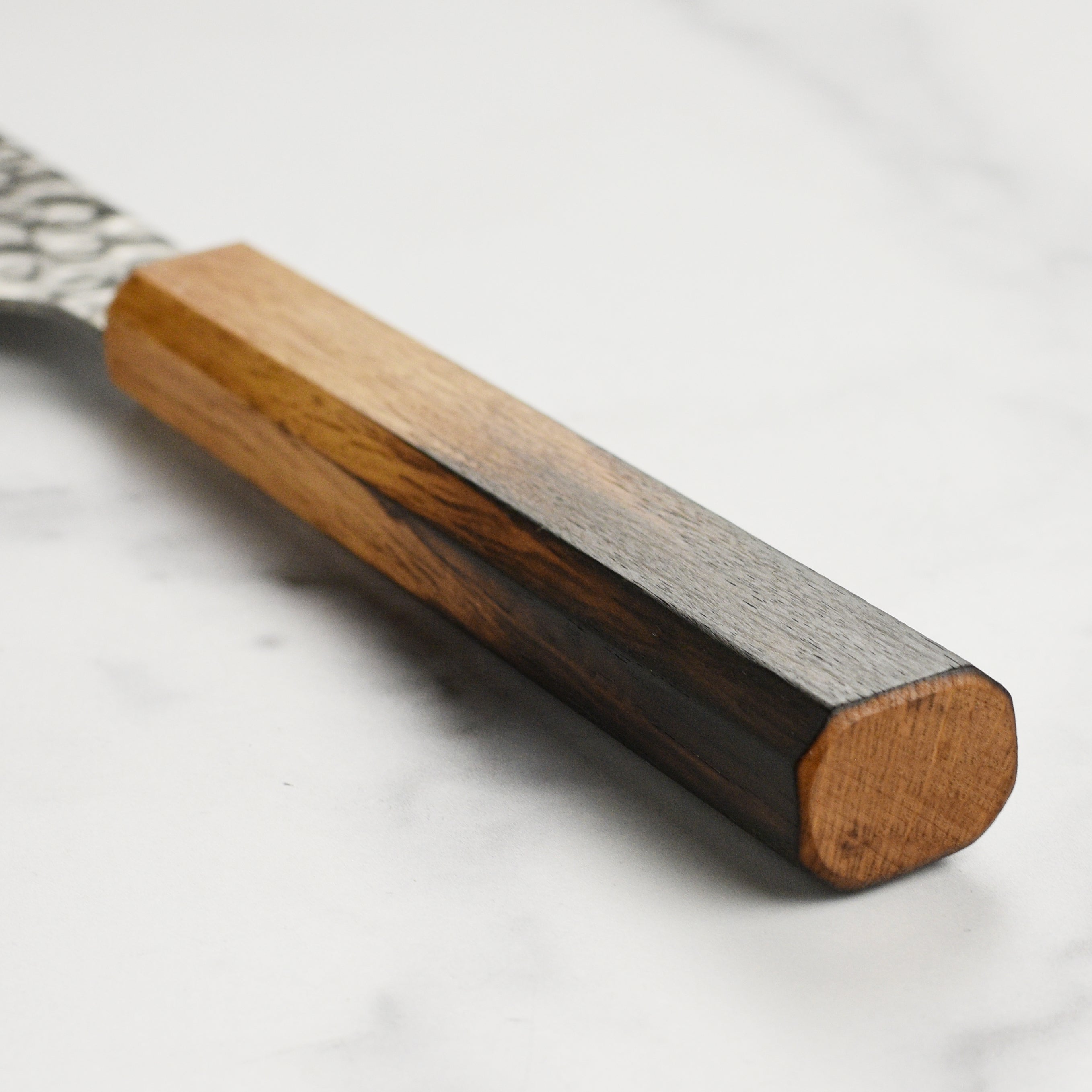 The octagonal burnt oak handle of the Sakimaru-Yanagiba knife, emphasizing its ergonomic design.