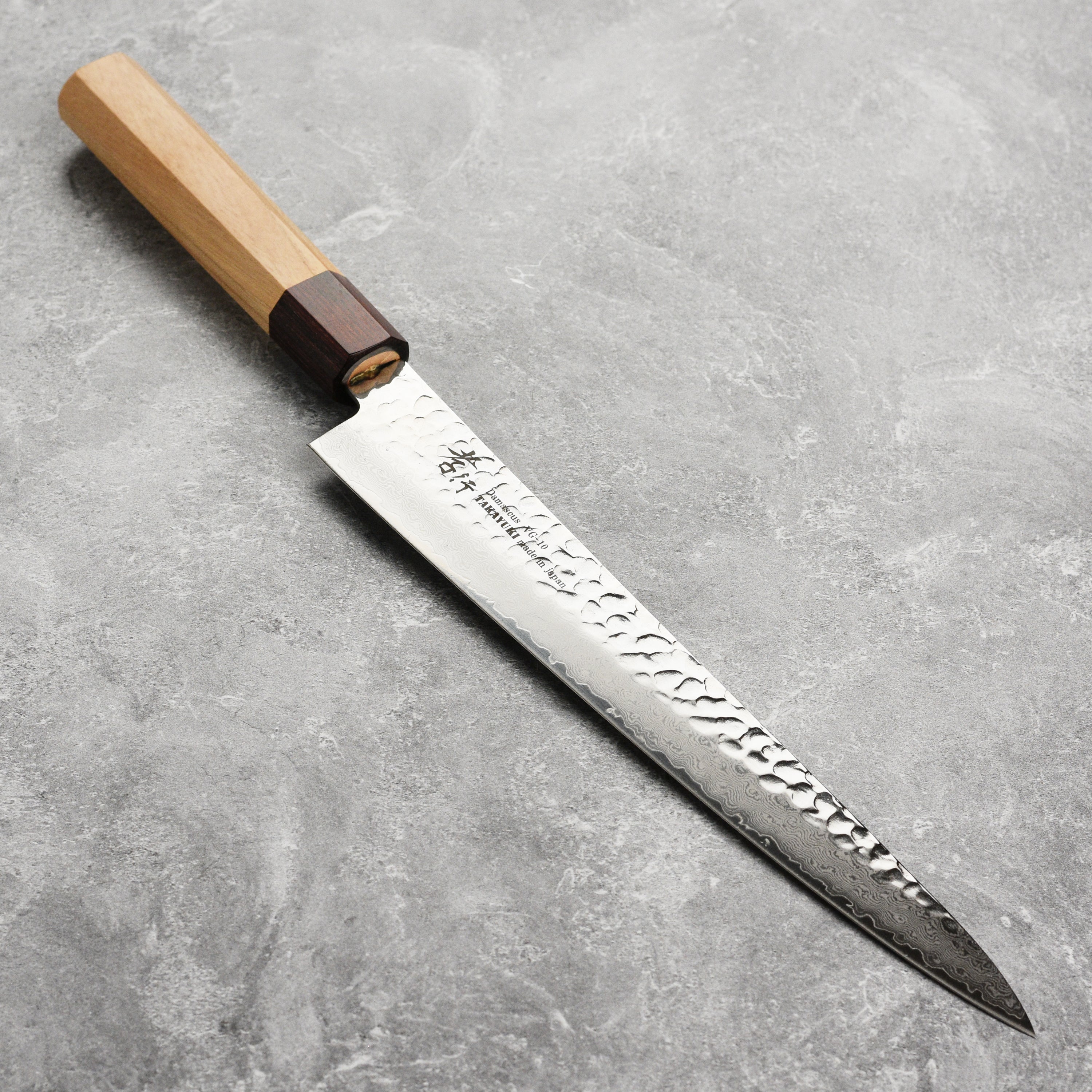 A detailed view of the Takayuki Tsuchime Damascus knife blade showcasing its layered pattern.
