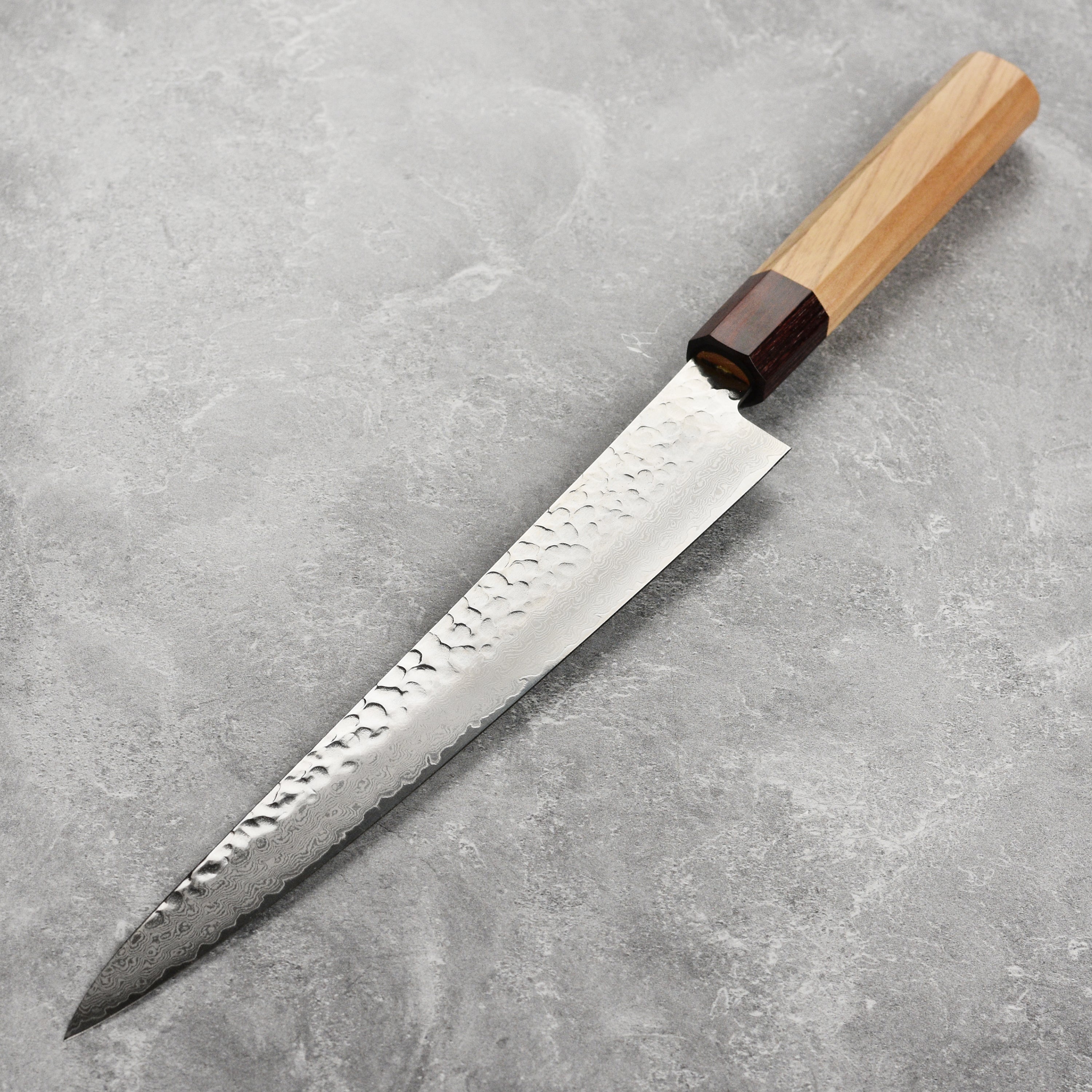 A detailed view of the Takayuki Tsuchime Damascus knife blade showcasing its layered pattern.