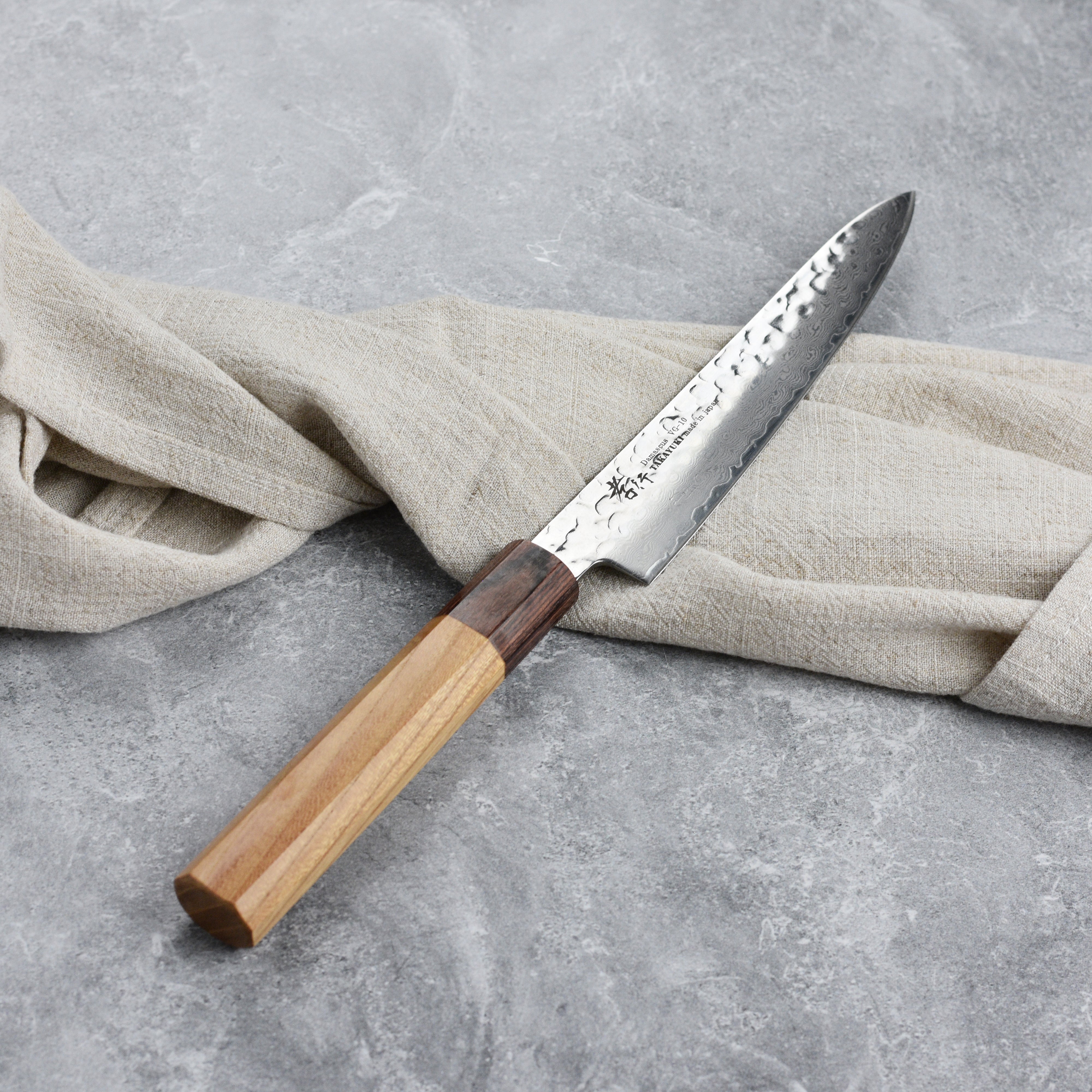 The premium Japanese damascus petty knife in action, cutting fresh vegetables on a wooden chopping board.