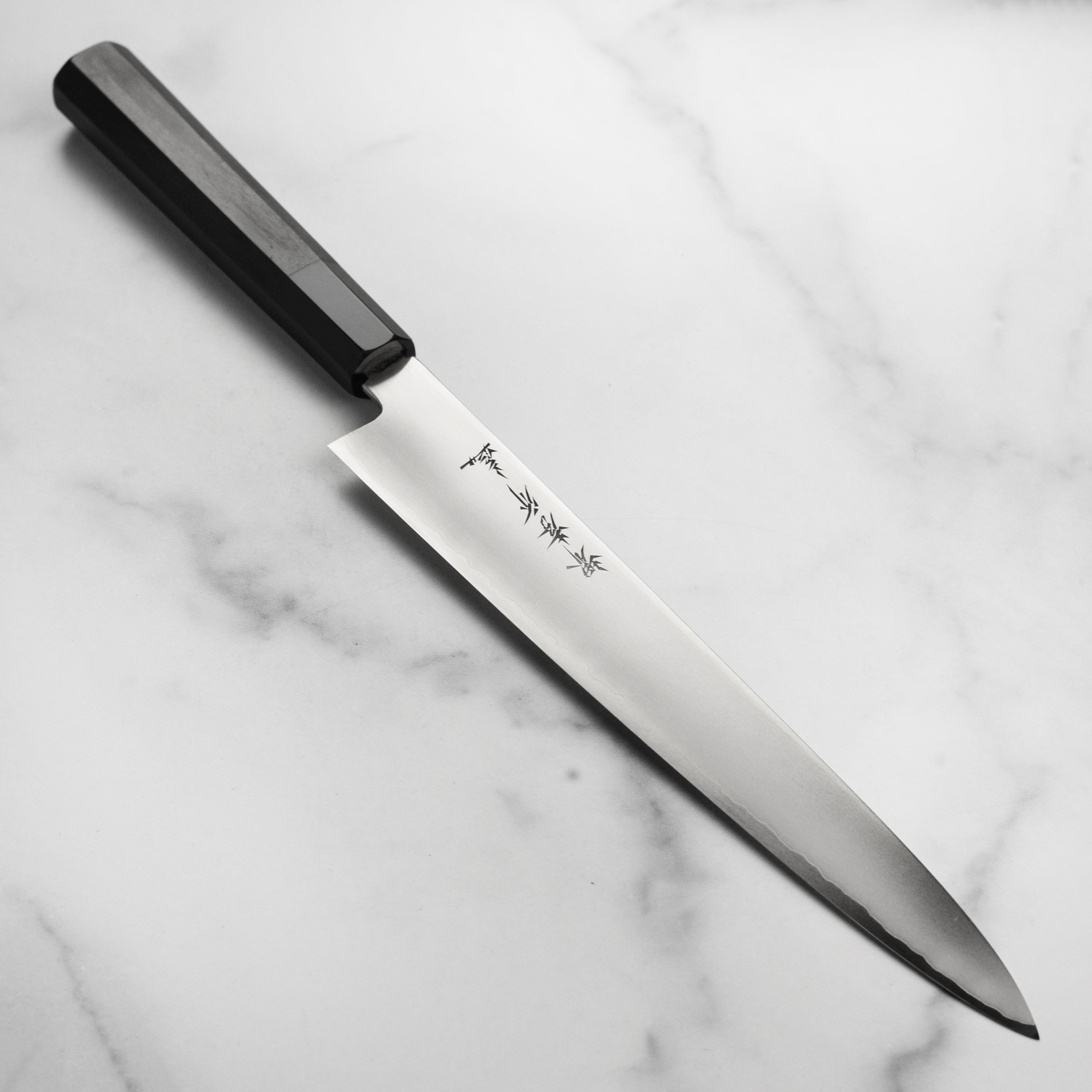 Side-angle view of the Takayuki Ginsan Sujihiki showcasing its 240mm stainless steel blade and ebony handle.