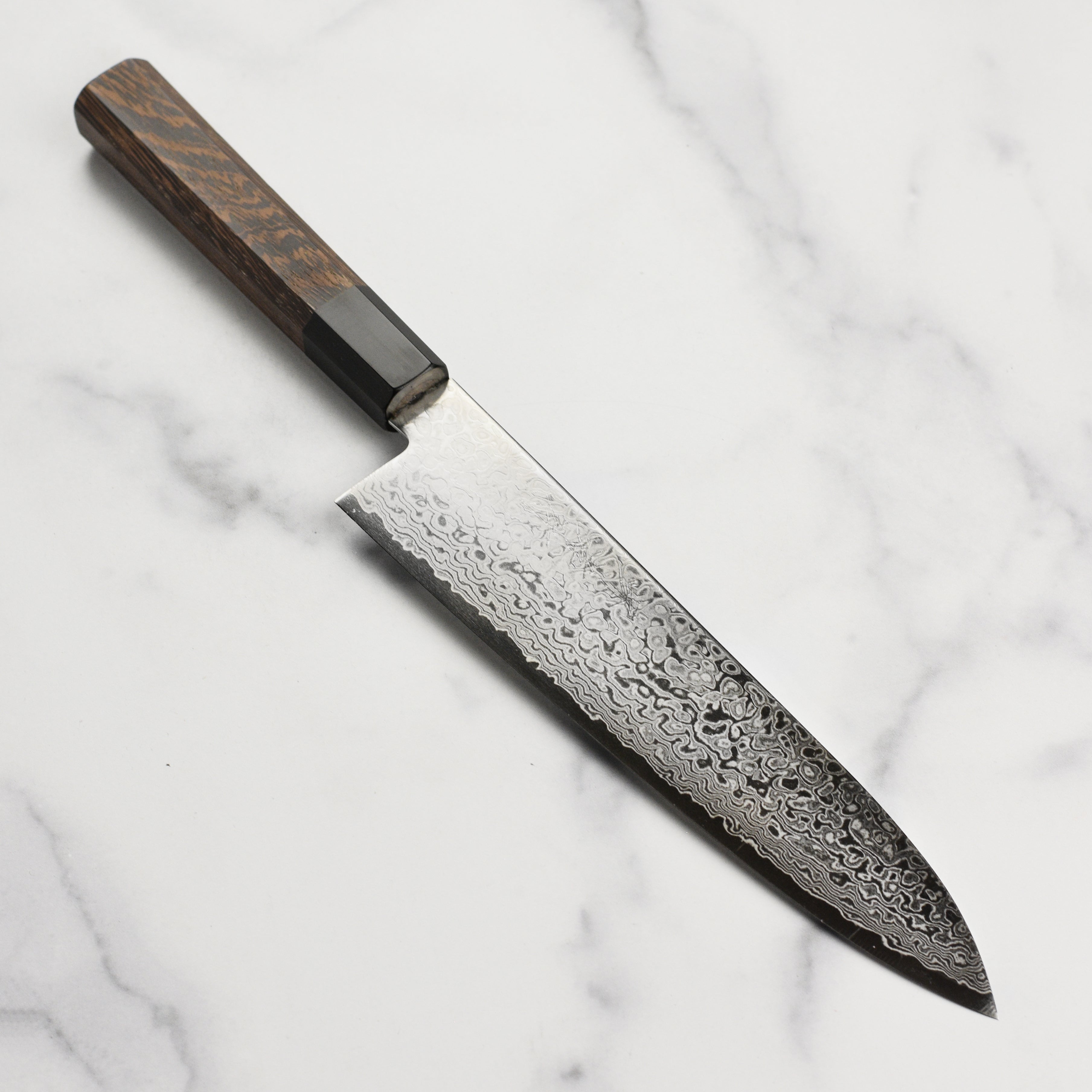 Ginga Damascus Chef Knife showcasing its beautiful mirror finish and sharp edge.