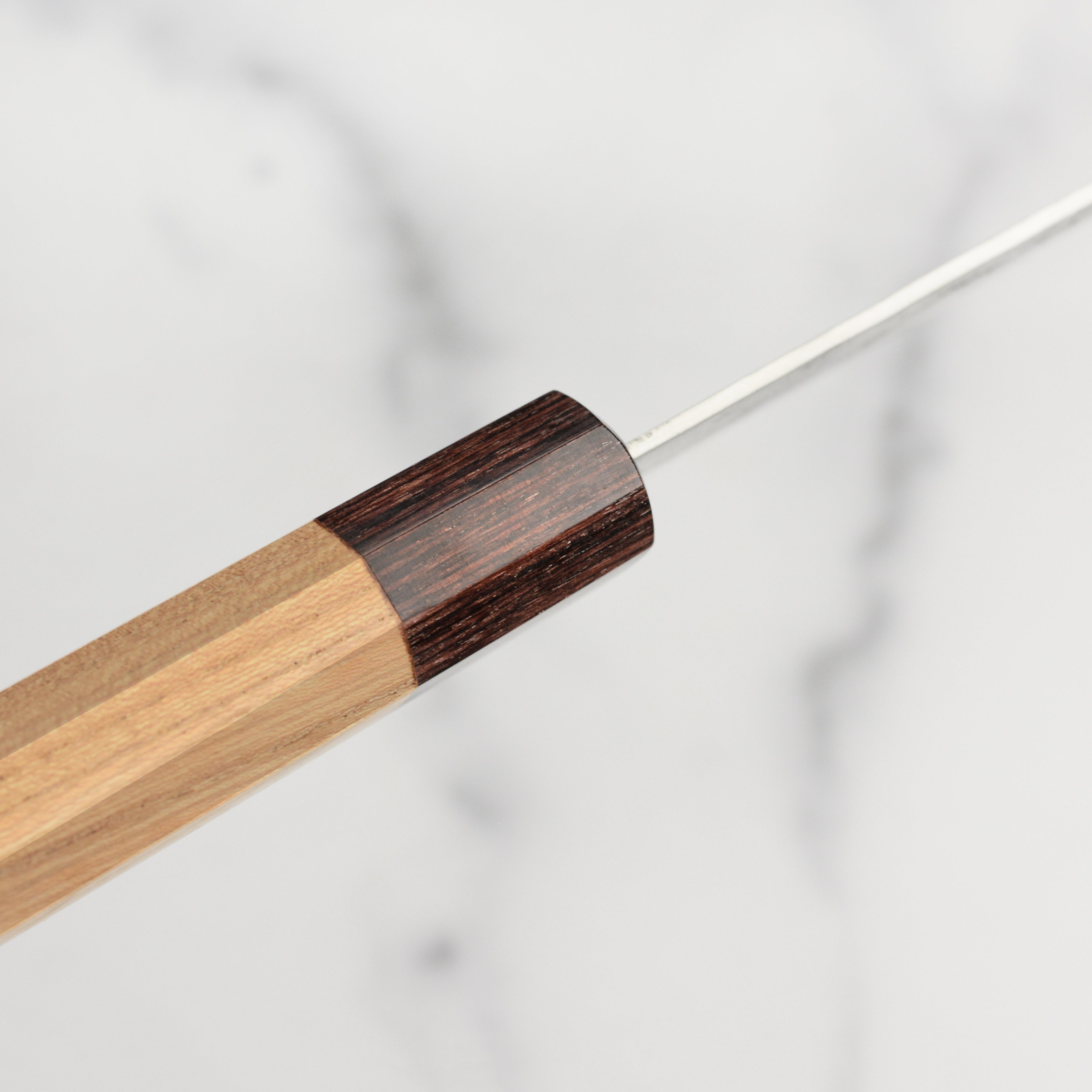 Elegant display of the Sakai Ginsan Nashiji Gyuto Knife with its Zelkova wood handle.
