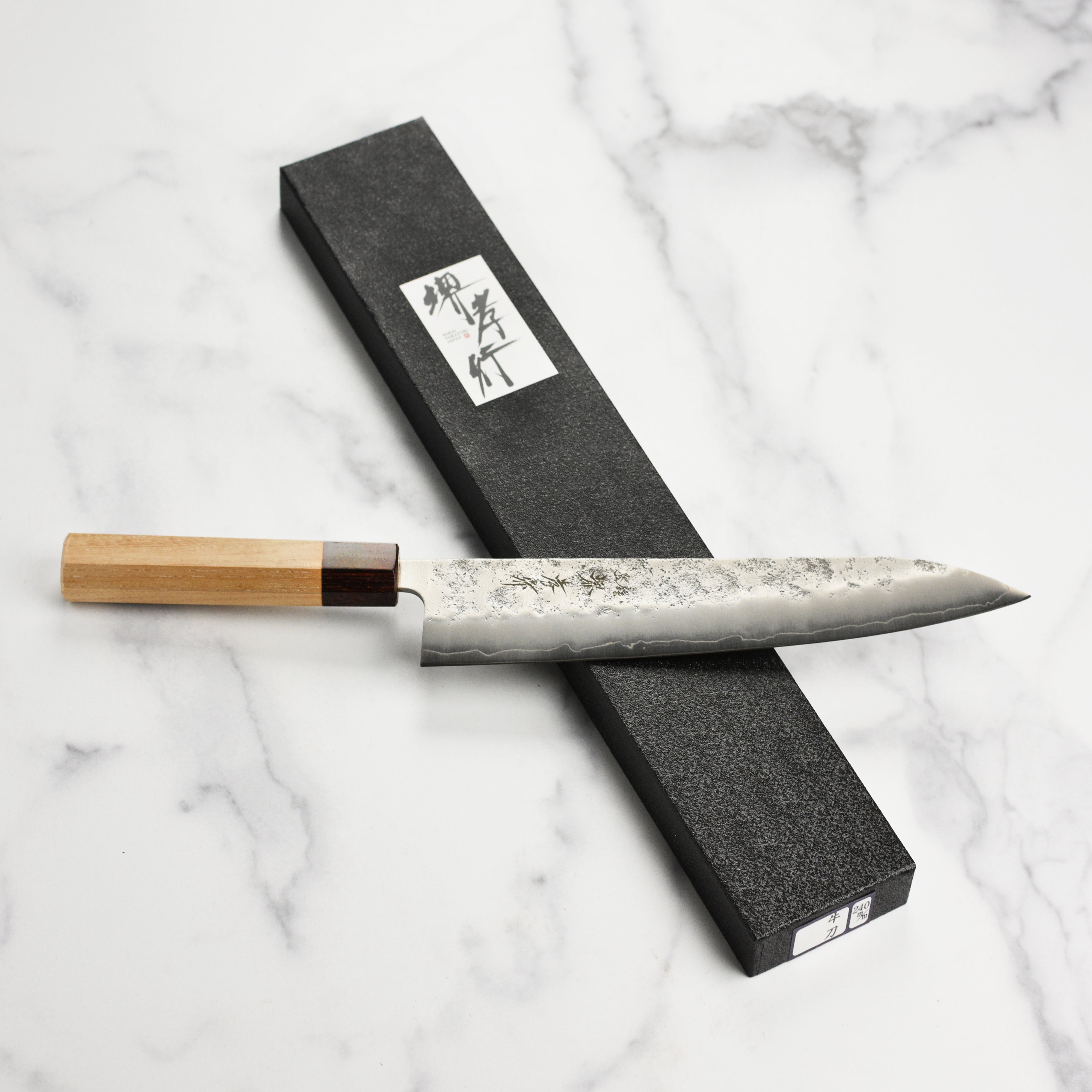 Elegant display of the Sakai Ginsan Nashiji Gyuto Knife with its Zelkova wood handle.