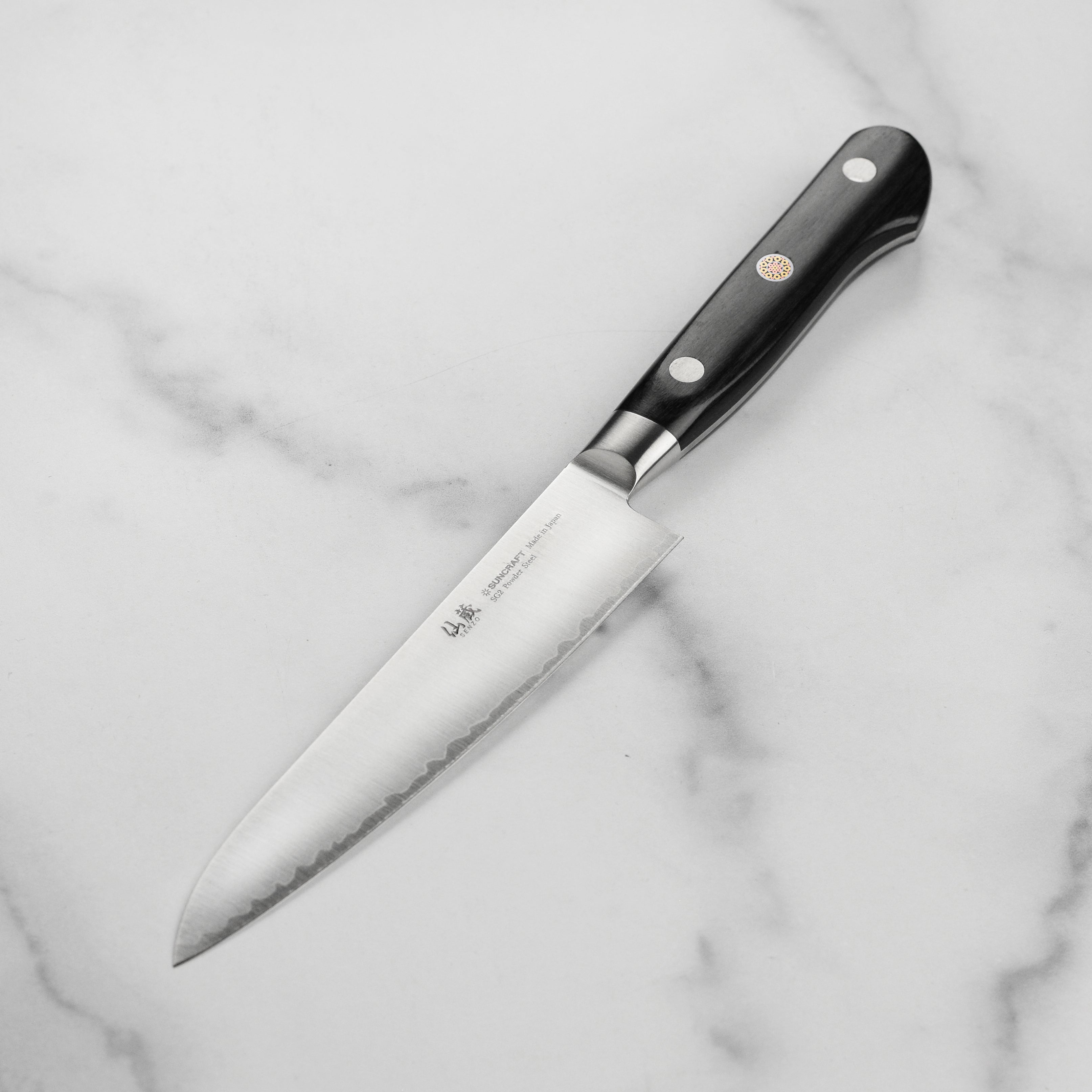 Senzo Artisan SG2 Utility Knife displayed on a wooden cutting board, emphasizing its design and craftsmanship.