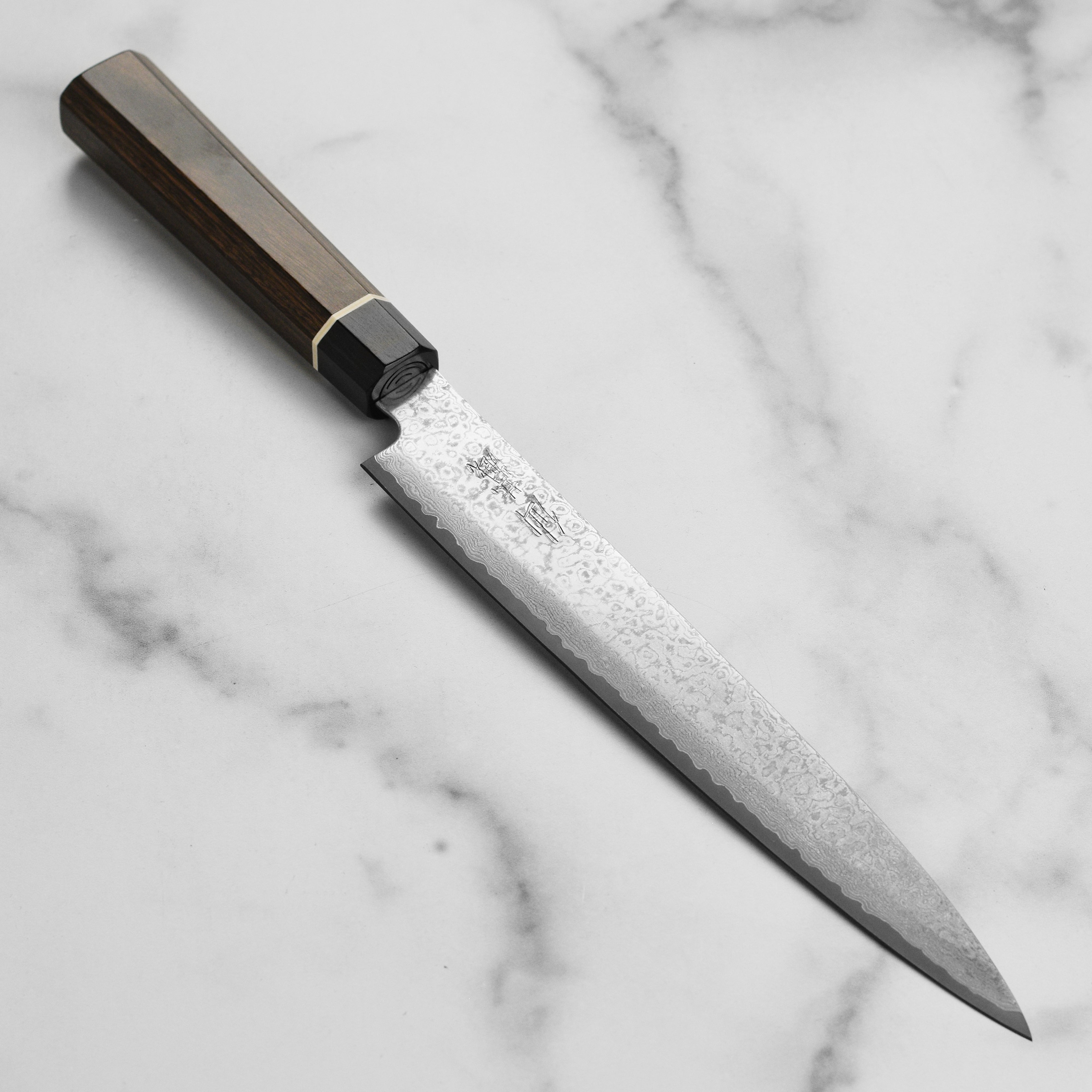 Close-up of the dark patterned Damascus blade with a Pakkawood handle