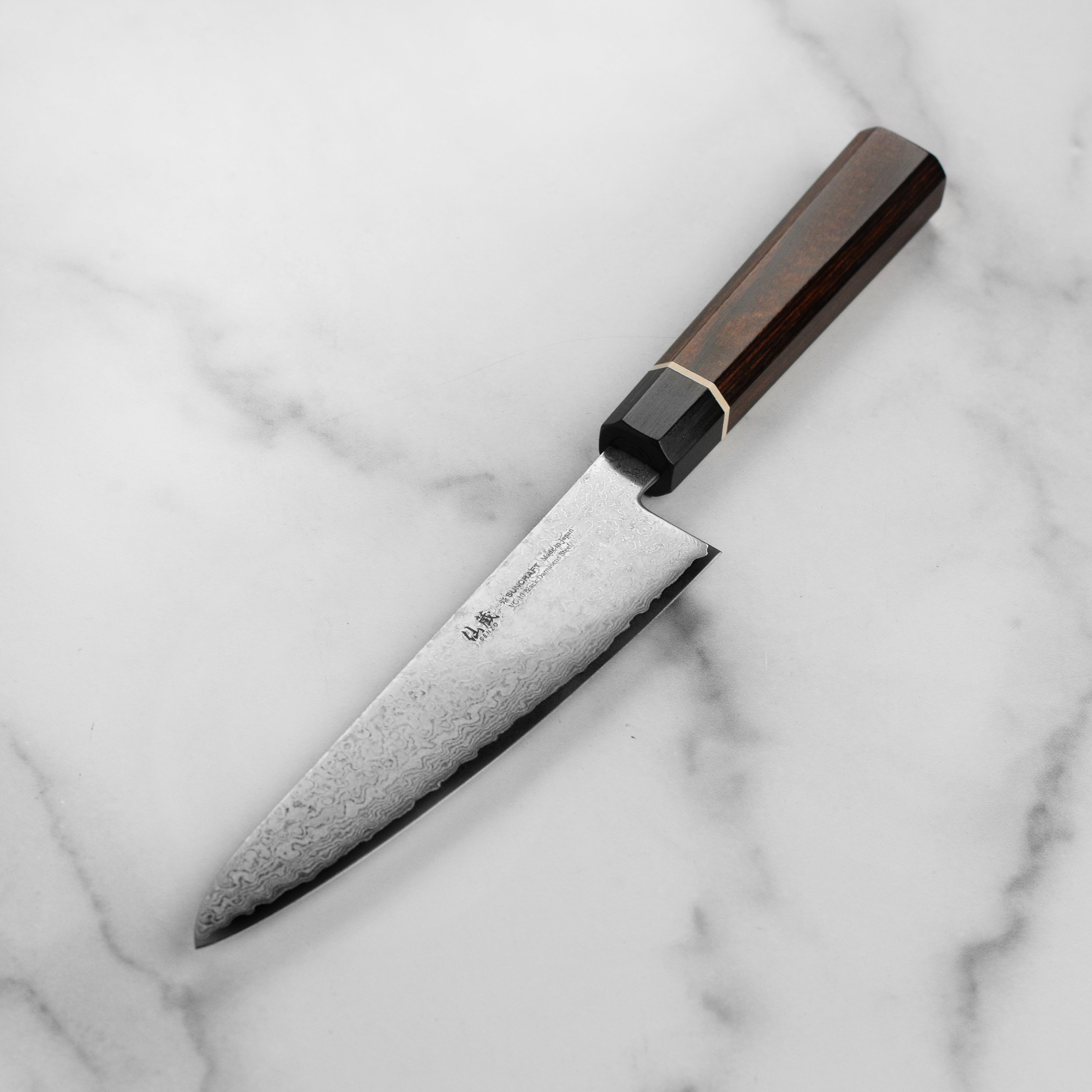 Japanese VG10 Damascus kitchen knife in hand, highlighting craftsmanship and handle design
