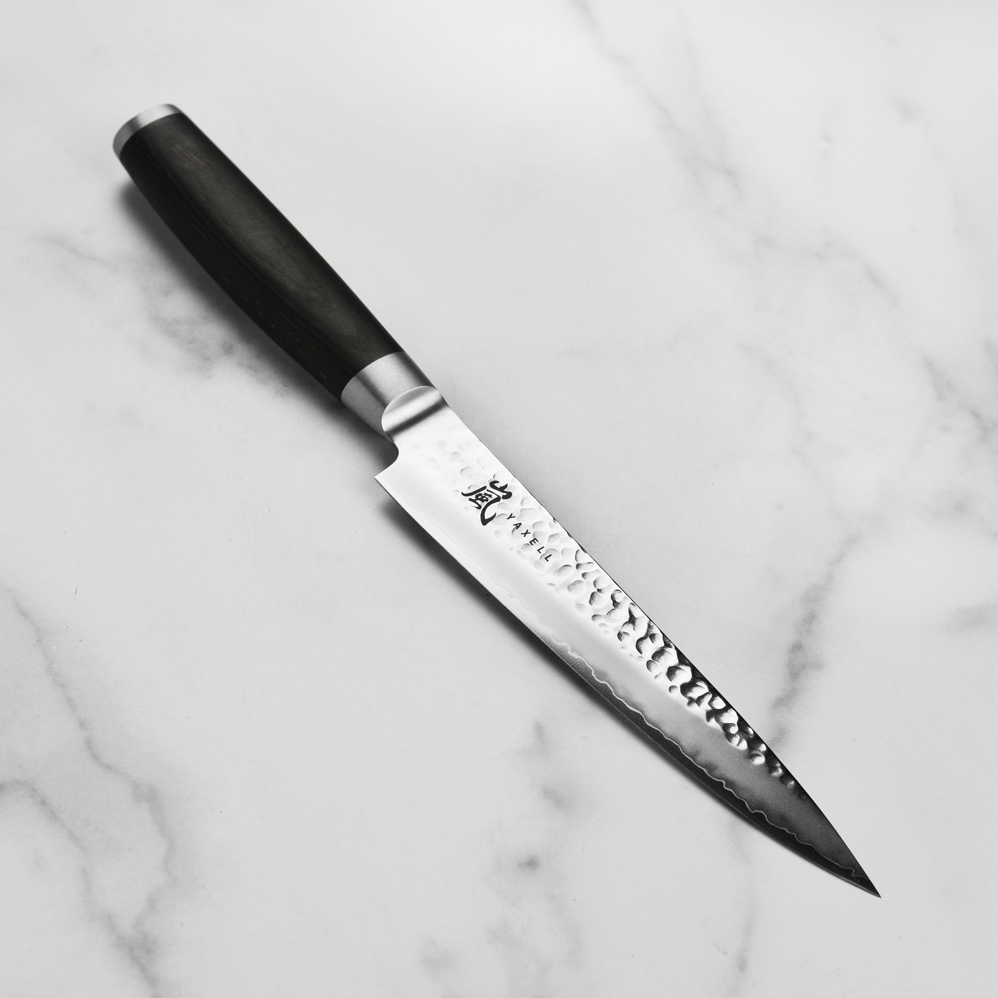 Yaxell Taishi 7 inch slicing knife showcasing its hammered finish and ergonomic handle.