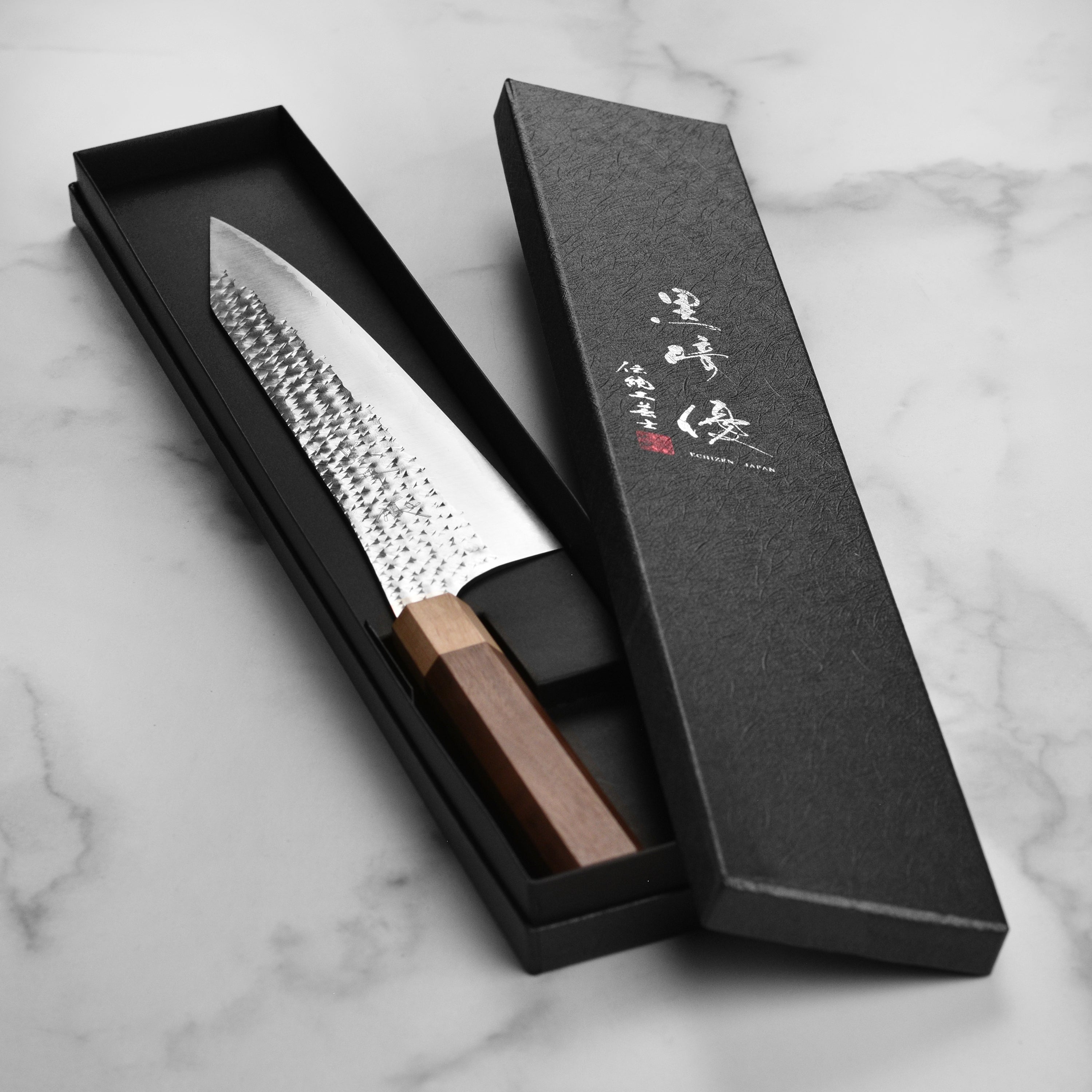 The Kurosaki Senko Ei 9.4" Gyuto knife on a wooden cutting board, showcasing its superior craftsmanship and ergonomic handle.
