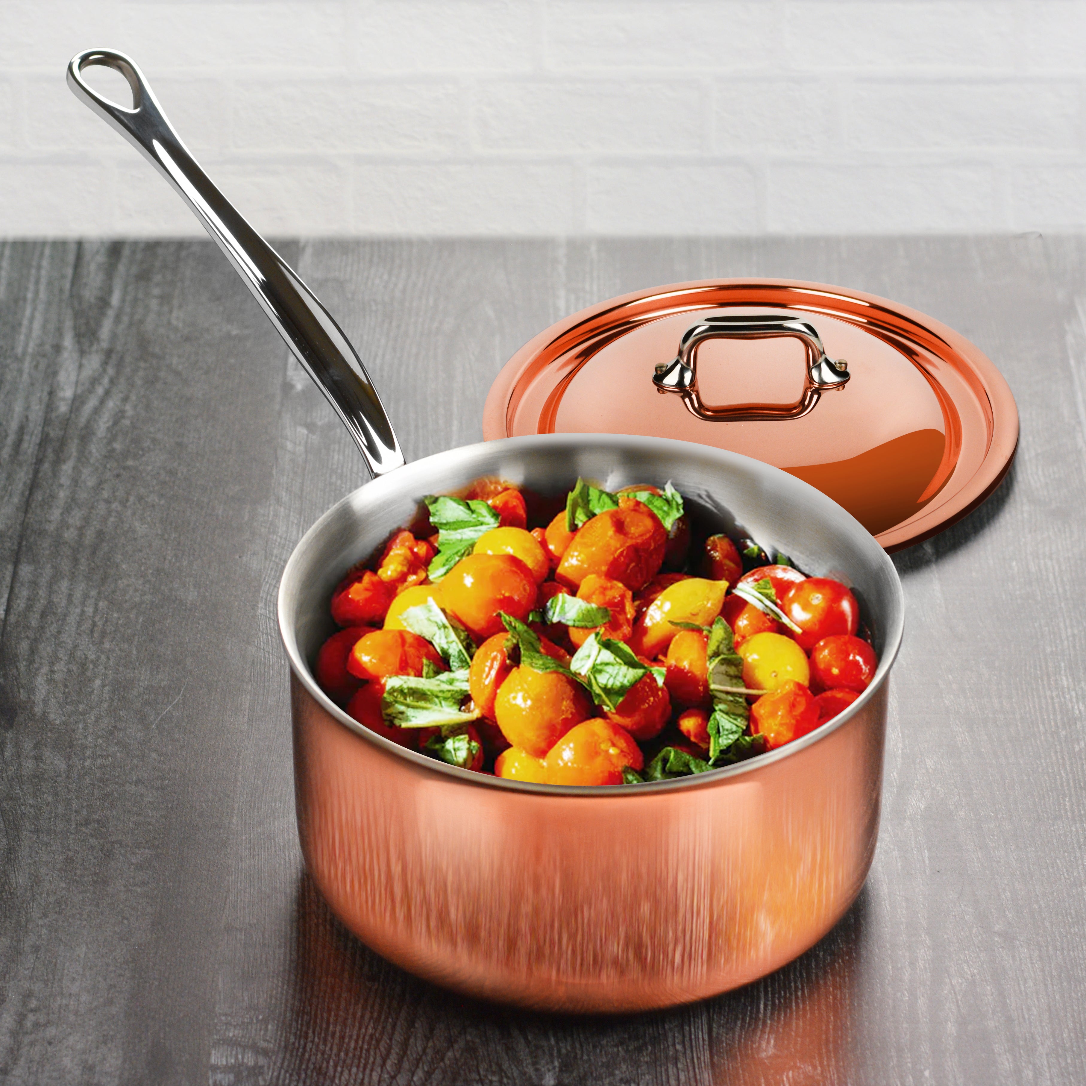 Close-up of stainless steel handles and flared rim of copper saucepan
