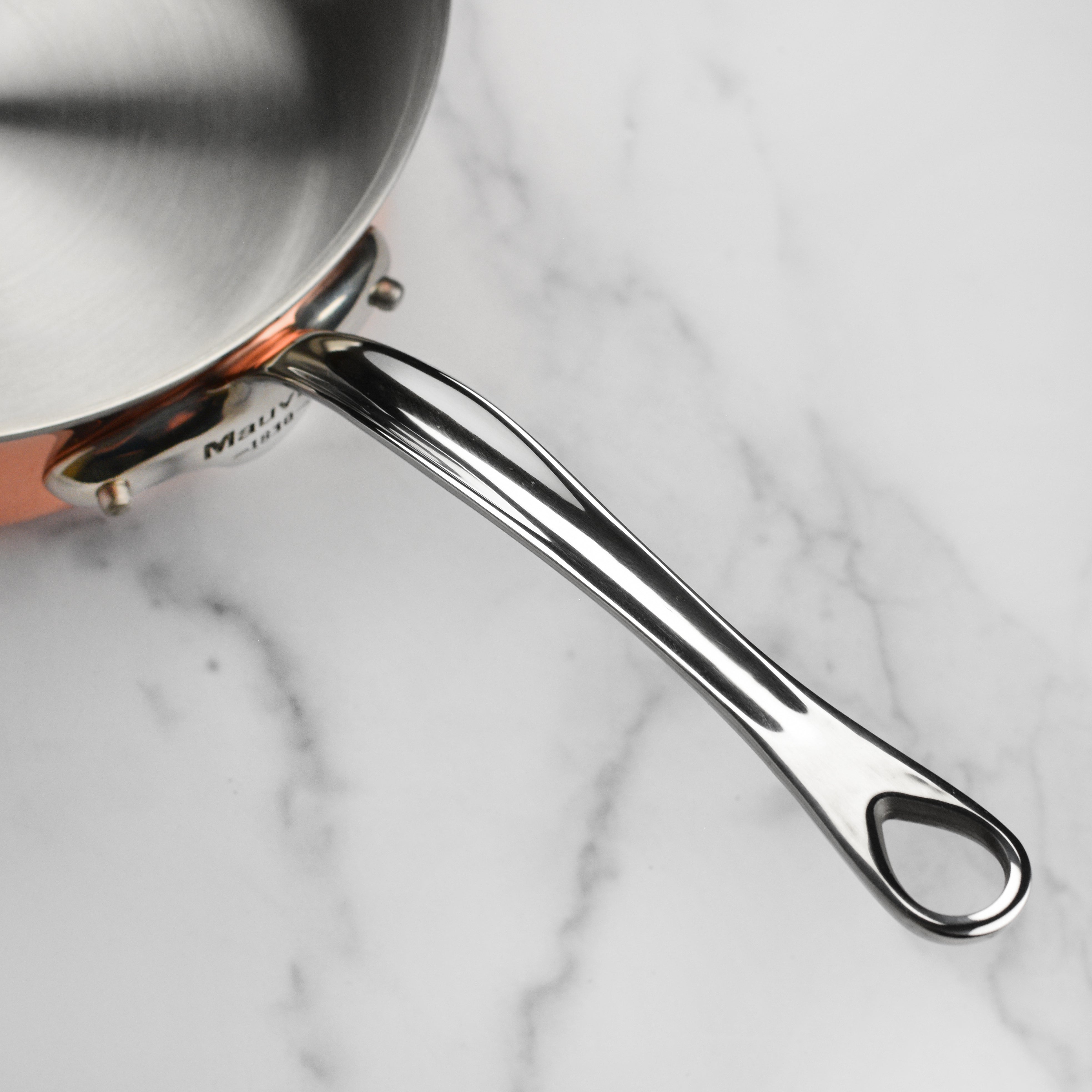 Close-up of Mauviel M6S copper induction saute pan with polished finish and stainless steel handles