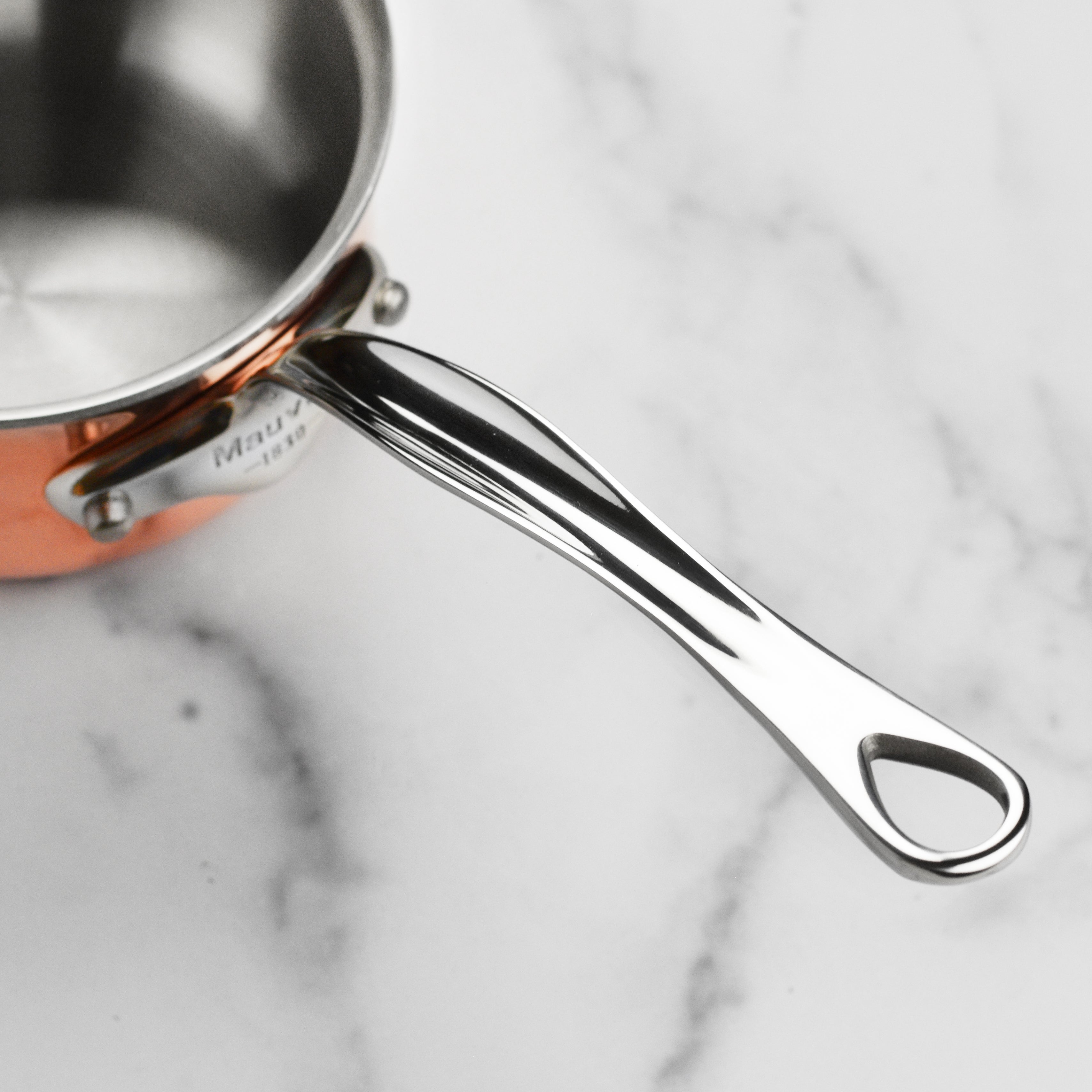 Close-up of the Mauviel copper saucepan showing its polished exterior and sturdy handles