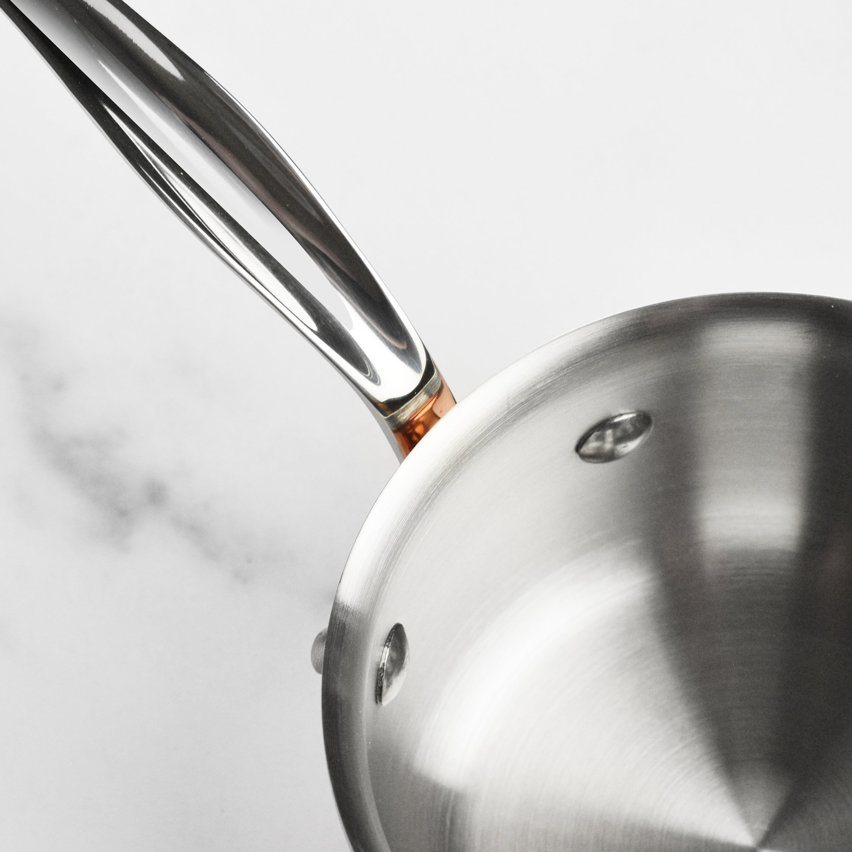 Close-up of the Mauviel copper saucepan showing its polished exterior and sturdy handles