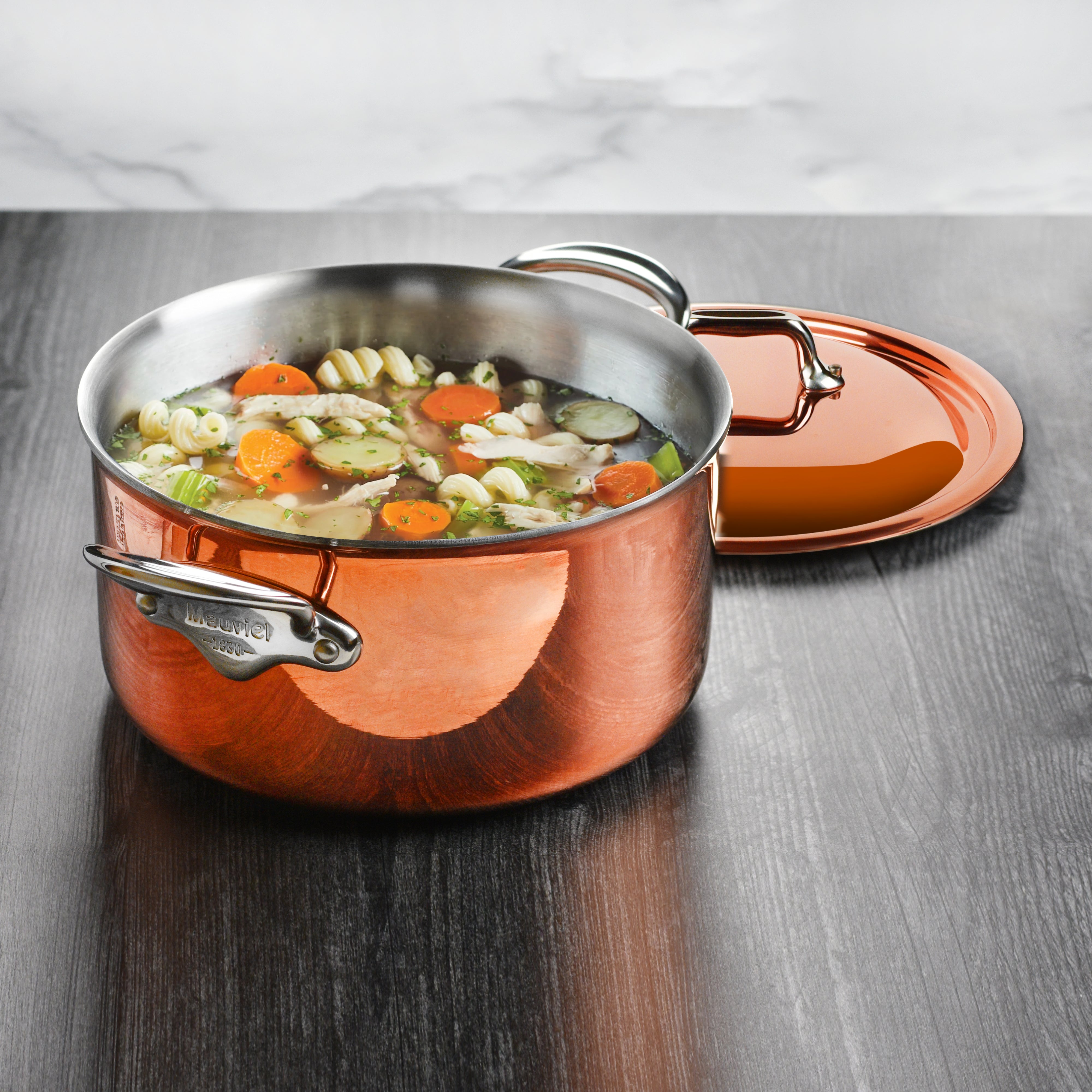 Premium copper stock pot in use on an induction cooktop, demonstrating versatility.