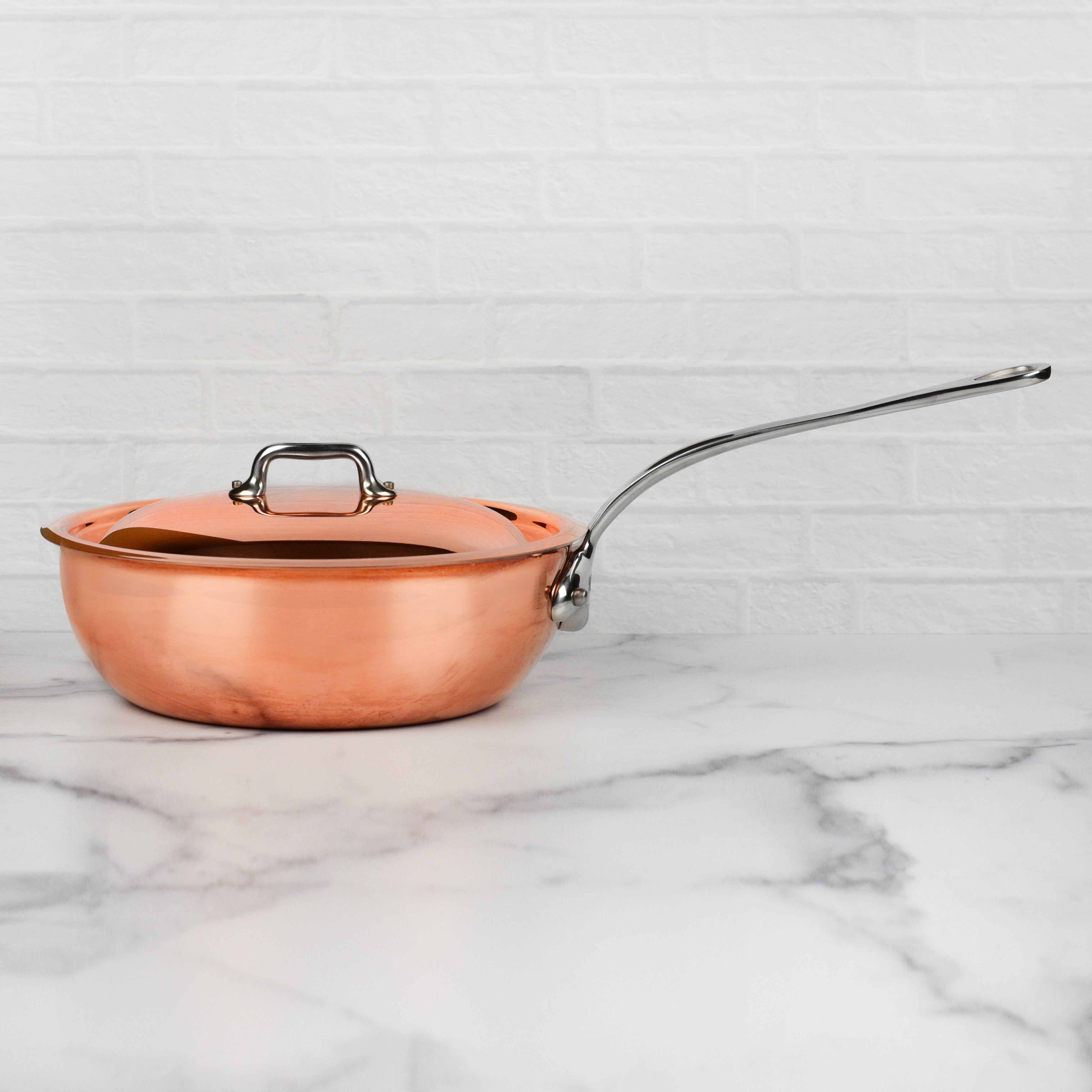 Copper saucepan with lid from Mauviel, highlighting the flared rim for drip-free pouring.