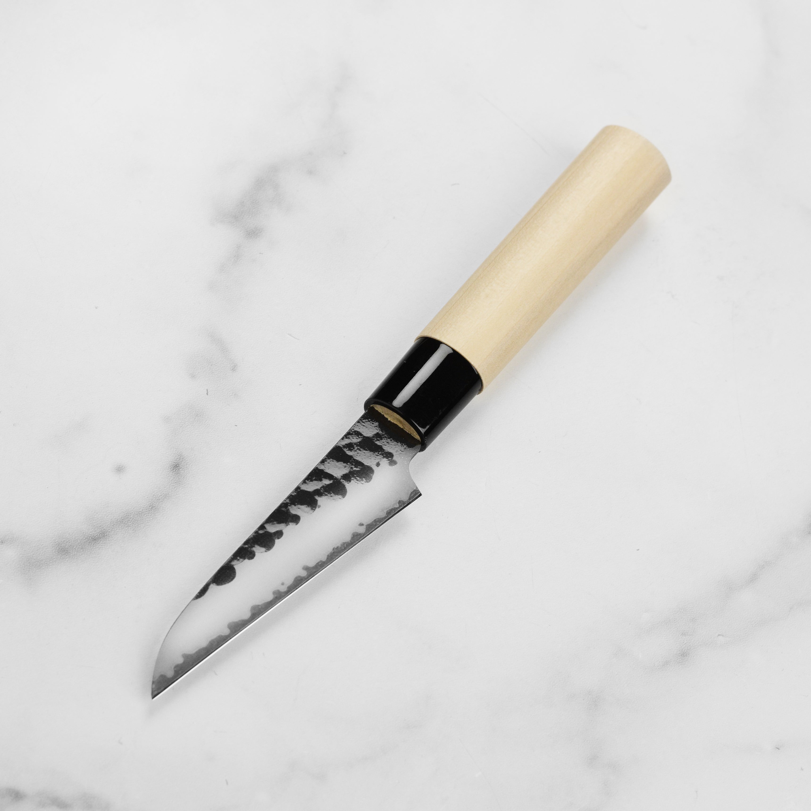 Tojiro VG-10 petty knife in action, slicing vegetables on a cutting board.