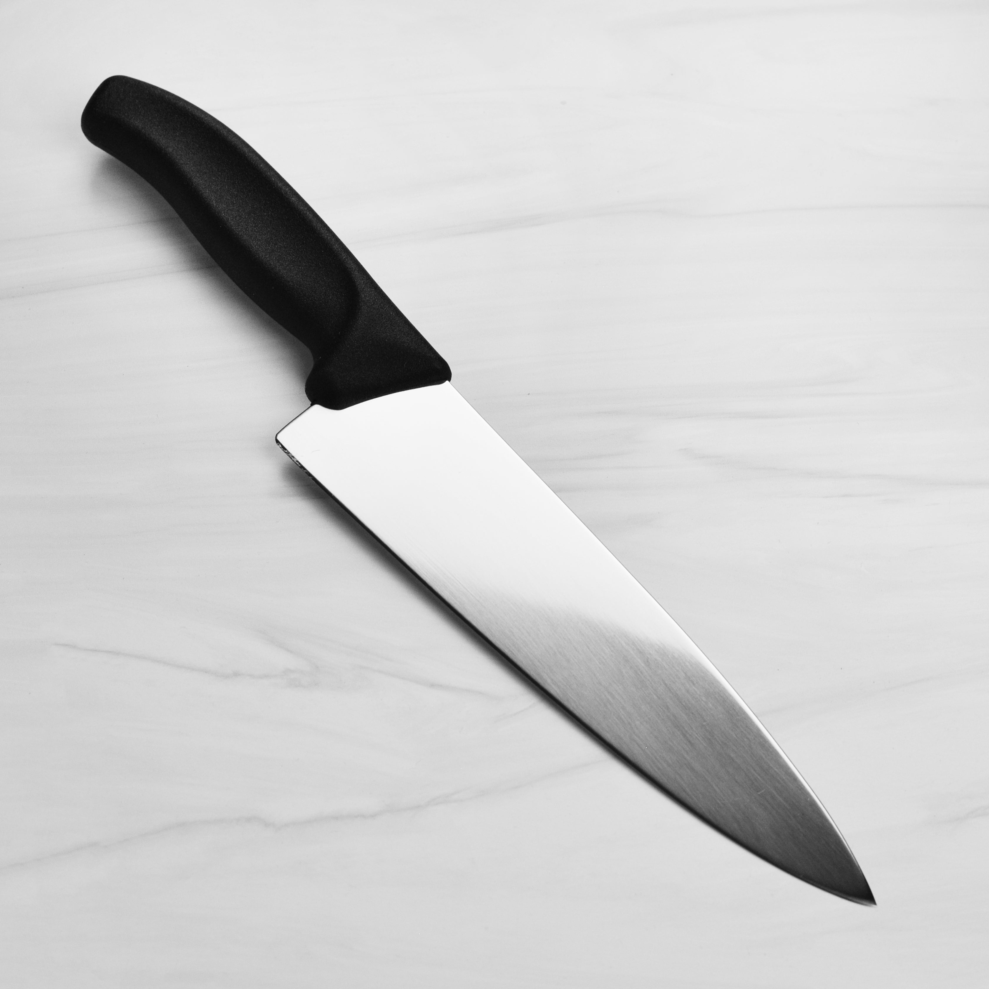 Swiss chefs knife displayed with fresh vegetables to demonstrate its cutting capability.