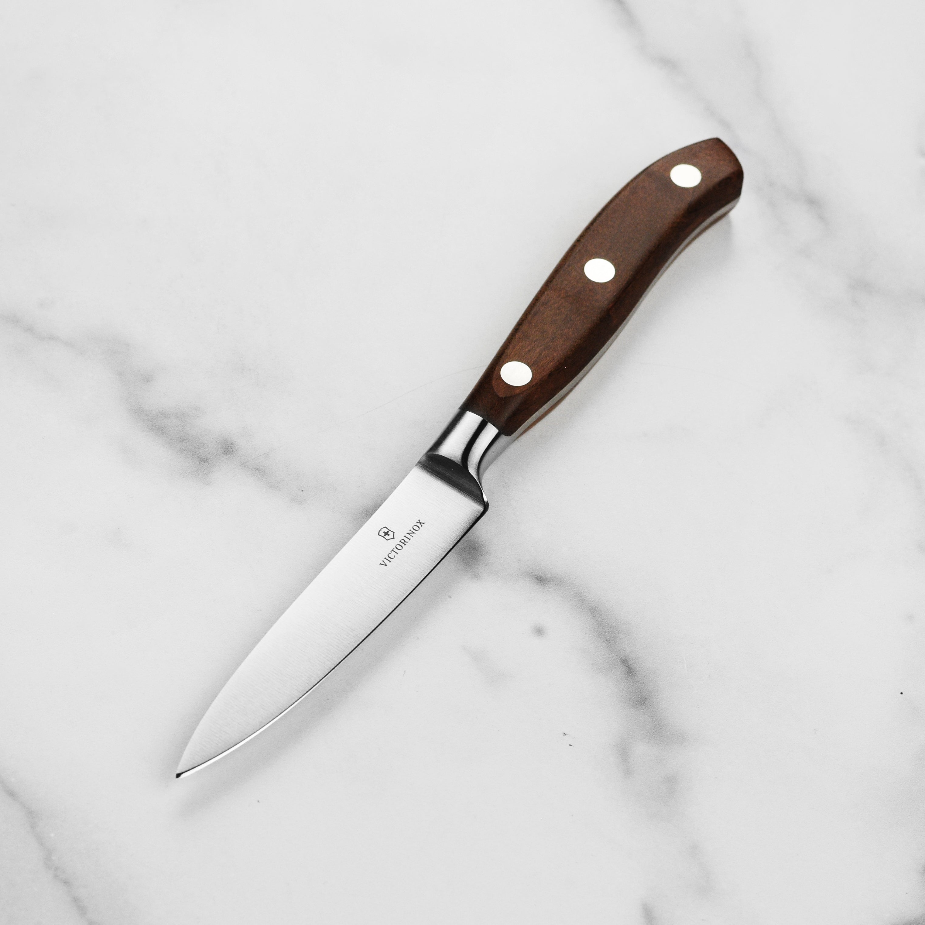 Victorinox paring knife angled overhead on cutting board with fresh produce