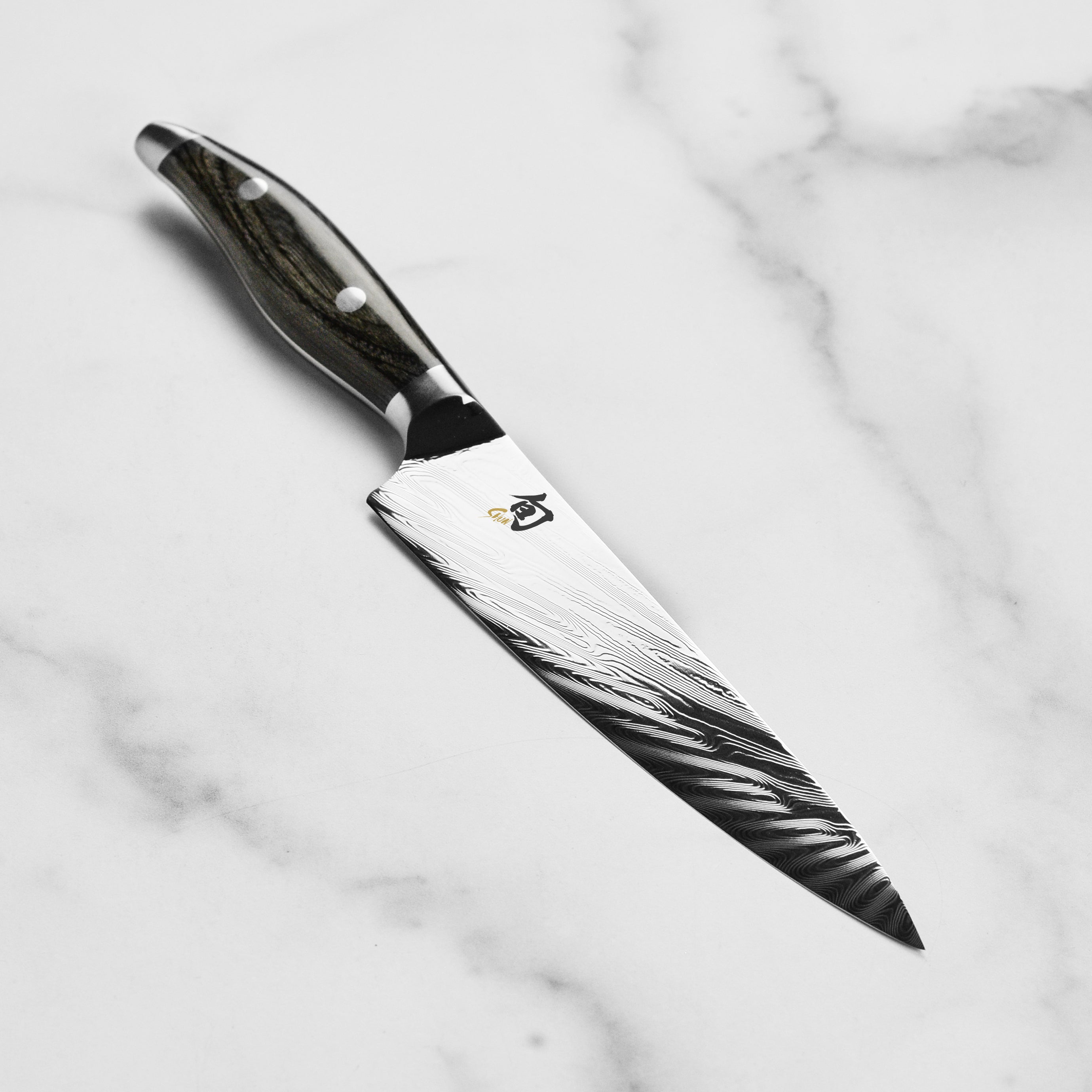 Side view of the Shun Nagare 6-Inch Utility Knife revealing the intricate Damascus pattern and sharp edge.