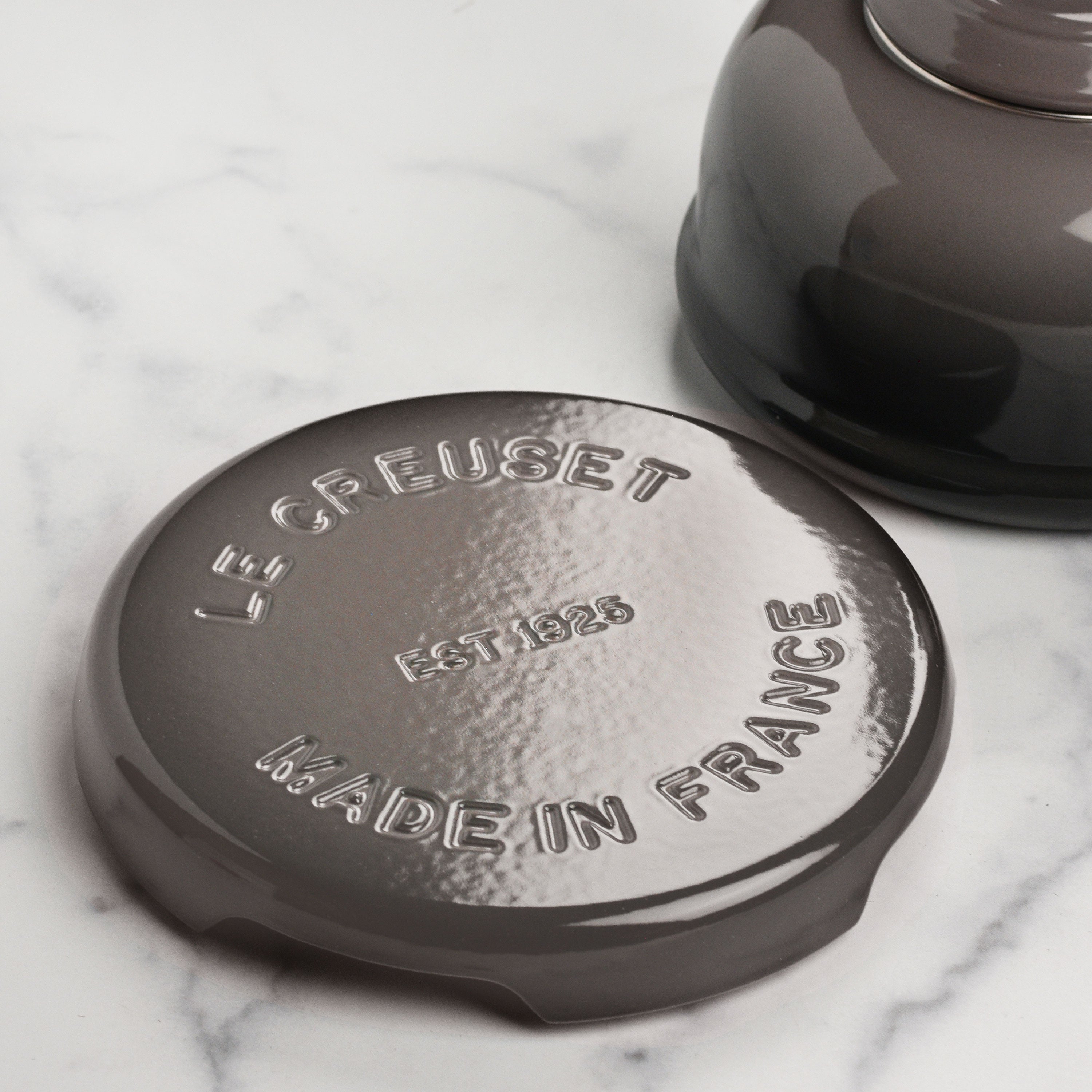 Elevated design of Le Creuset trivet protecting a wooden table from heat.