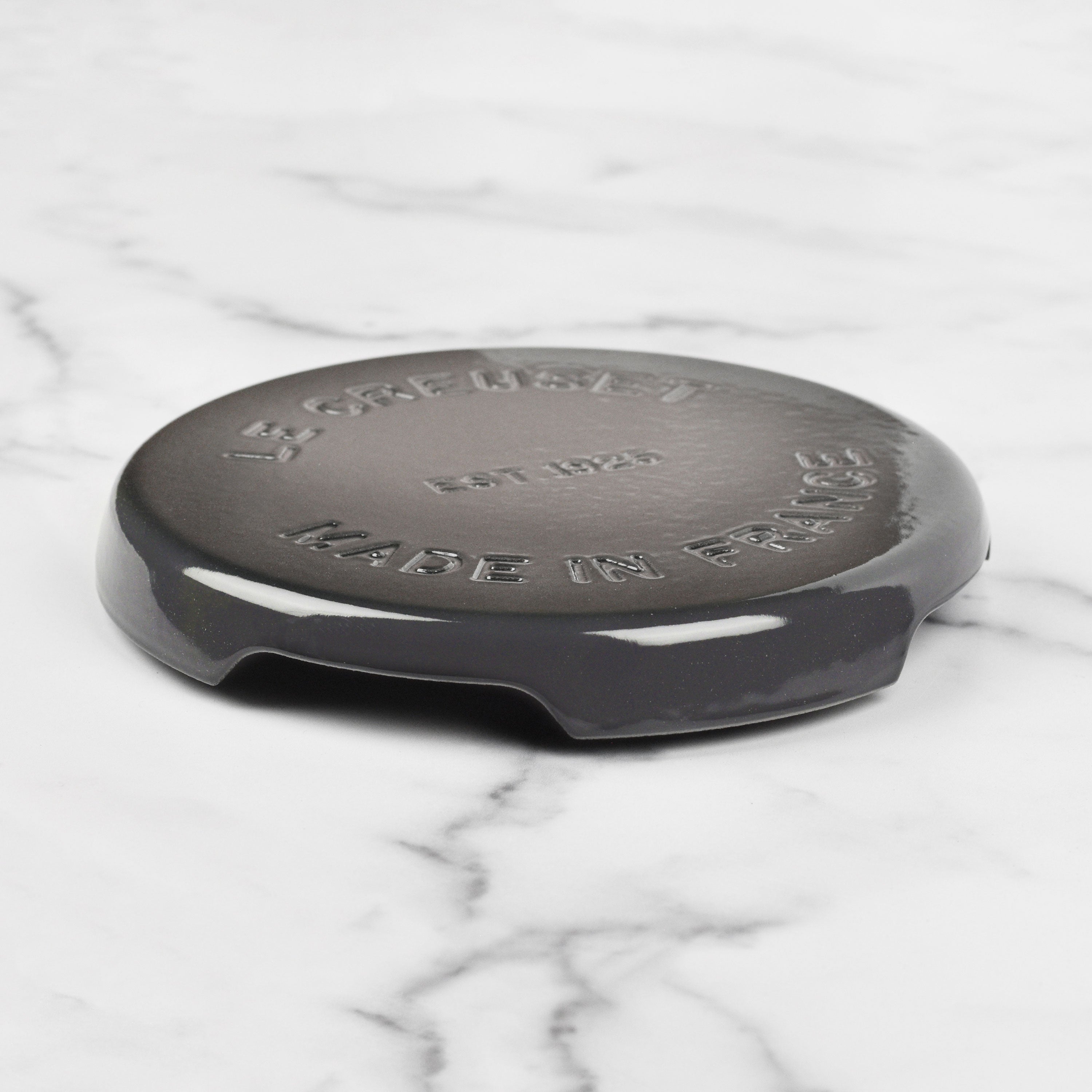 Le Creuset cast iron trivet in oyster color, perfect for hot dishes.