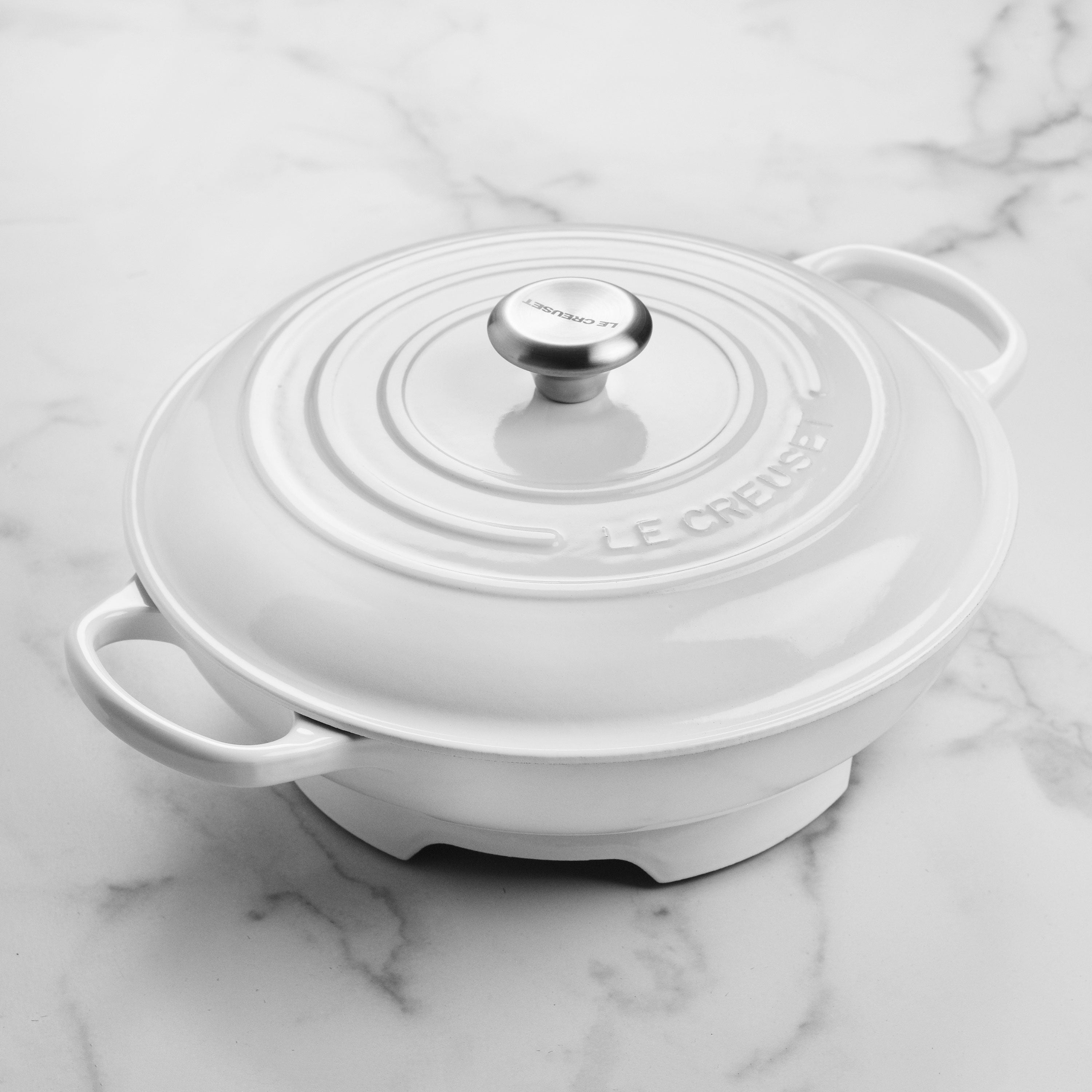 Stylish white round cast iron trivet protecting a wooden table from hot pots