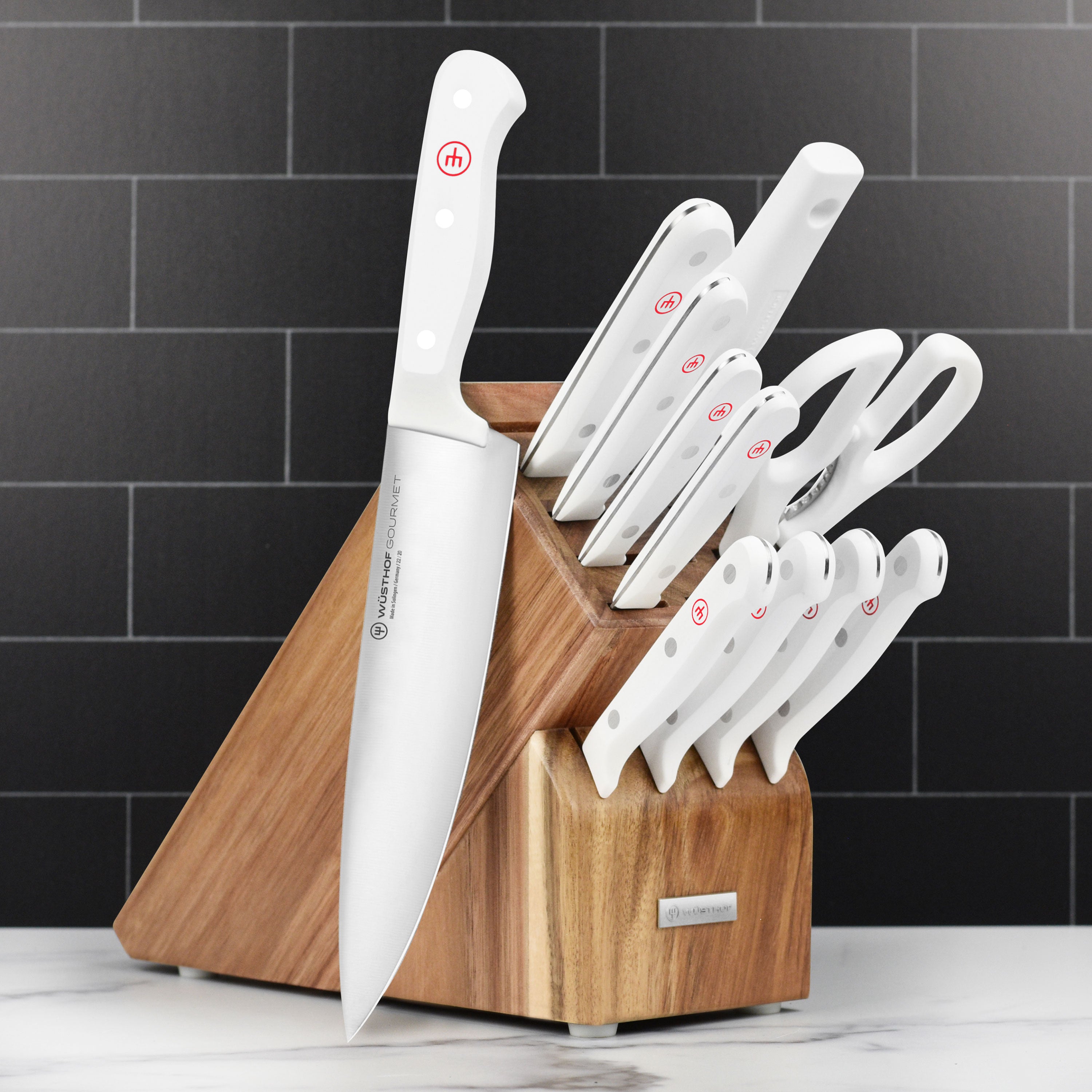 Wusthof Gourmet 12-piece German kitchen knife set with white handles on a wooden cutting board