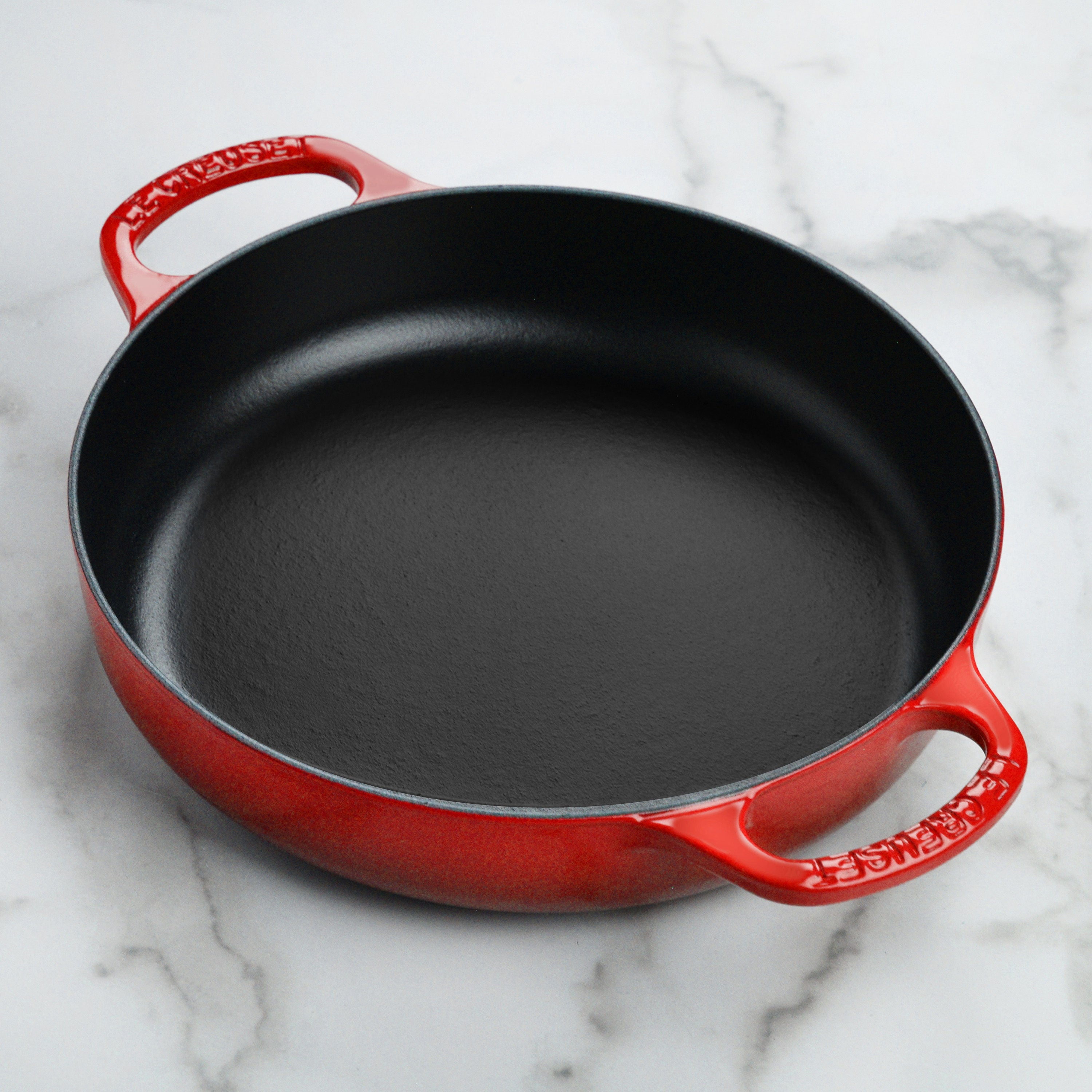 Le Creuset cast iron pan on a stove, demonstrating its compatibility with various cooktops.