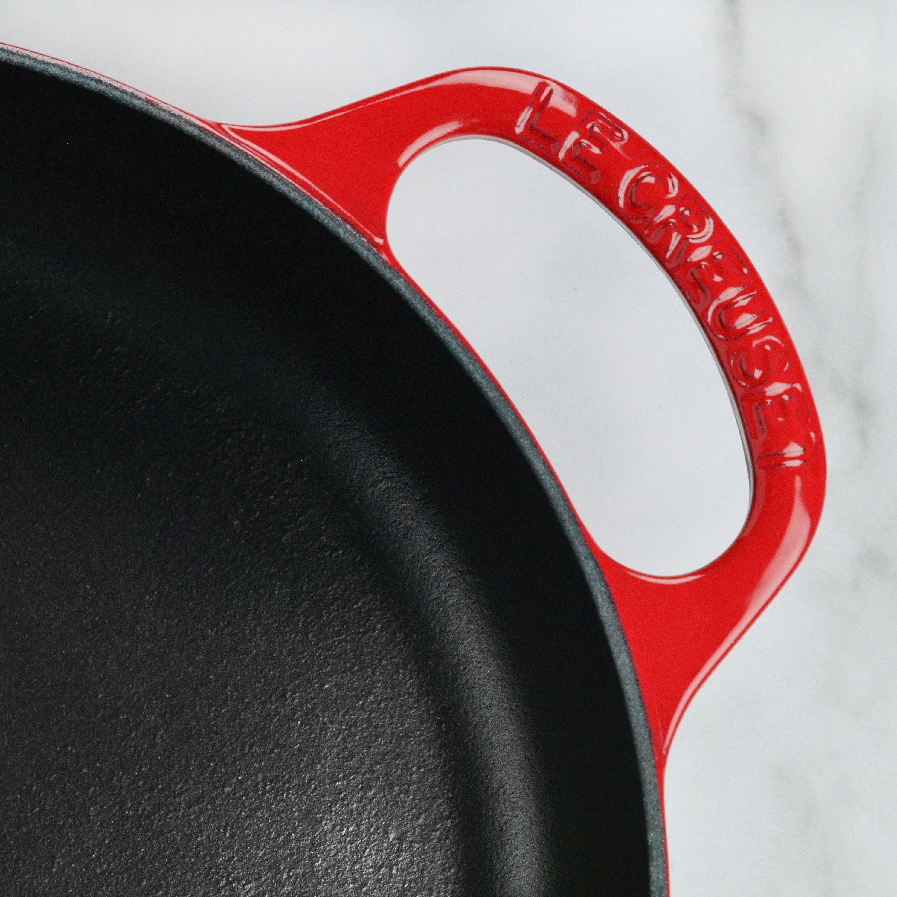 Le Creuset cast iron pan on a stove, demonstrating its compatibility with various cooktops.