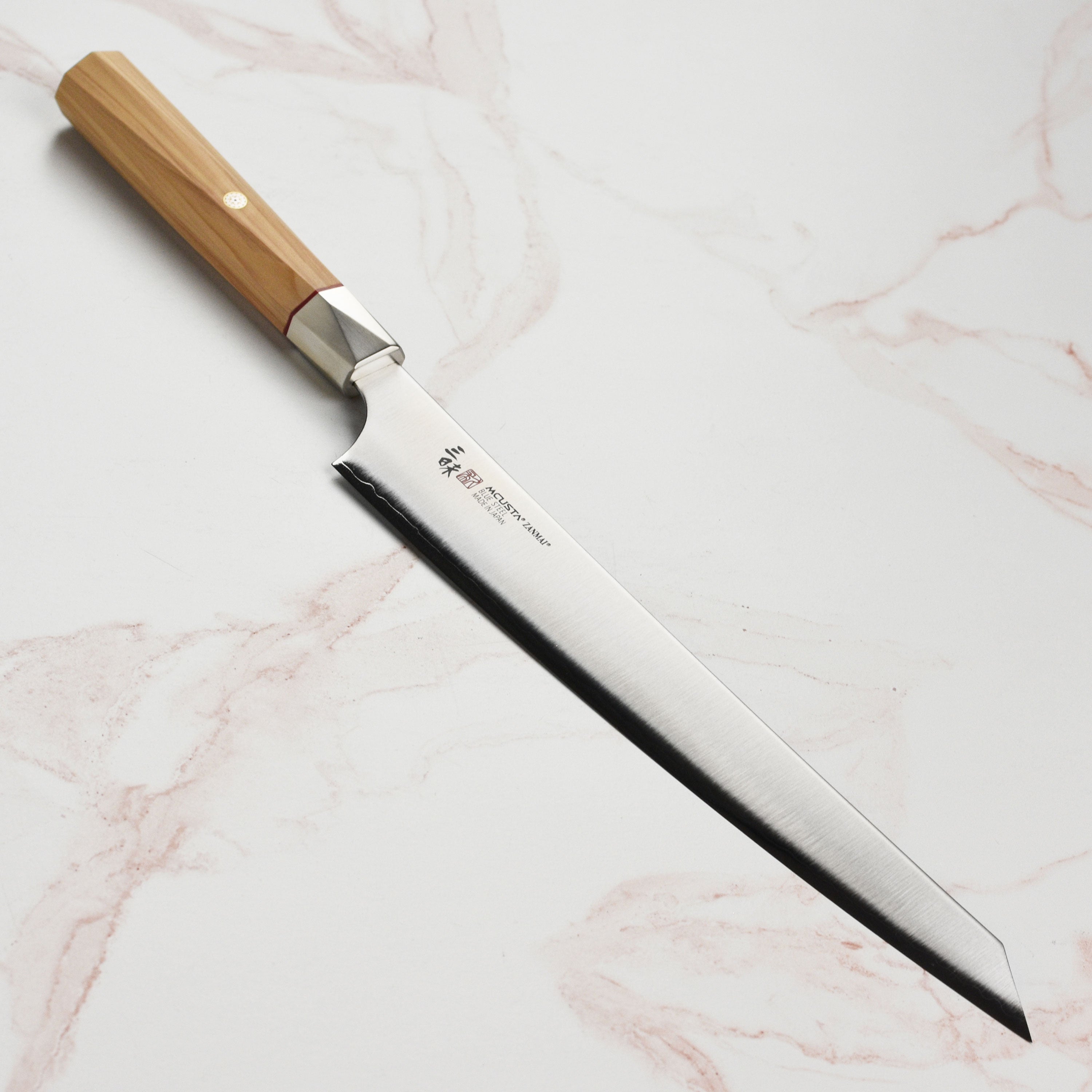 Close-up of the Zanmai Beyond Aogami Super 9.4-inch sujihiki showing the sharp edge and handle detail