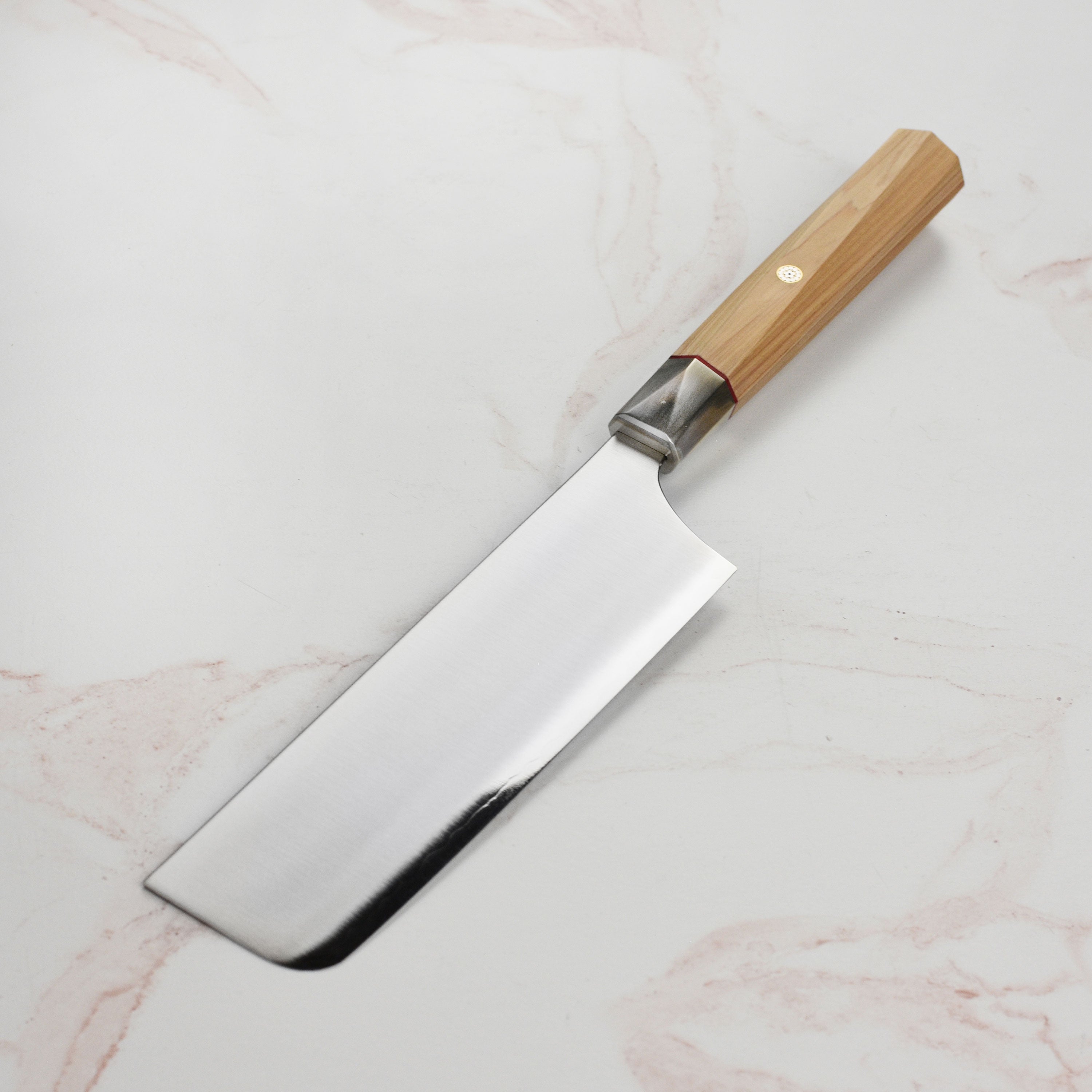 Japanese Nakiri knife with Hinoki wood handle resting on cutting board
