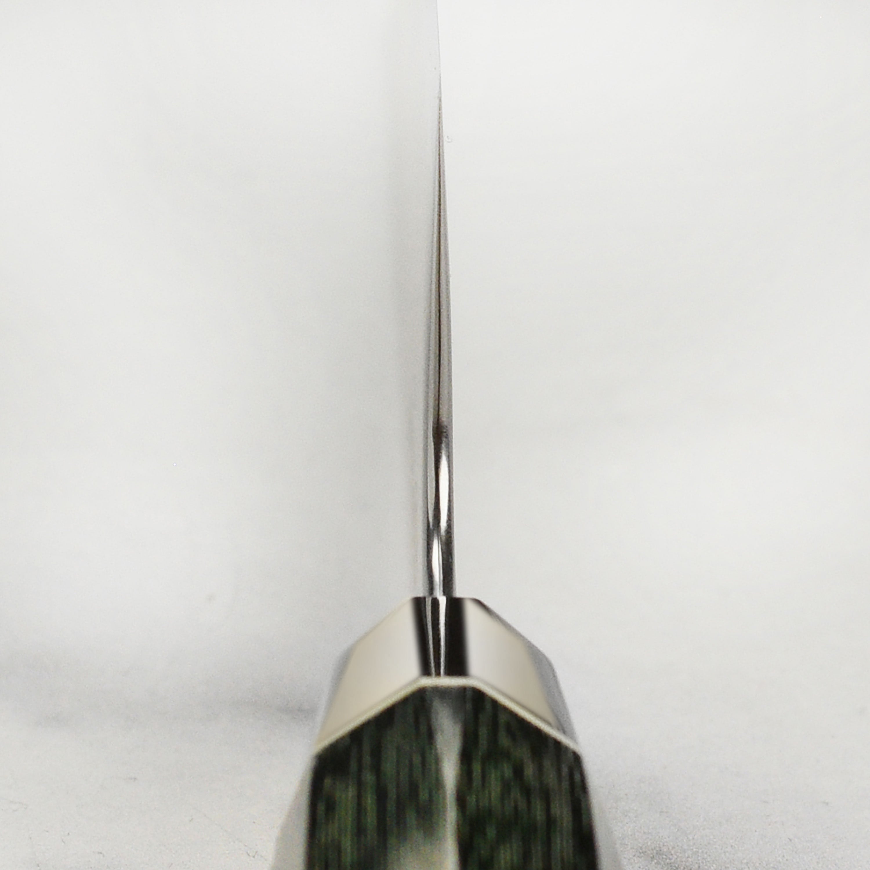 Zanmai Revolution SG2 kitchen knife displayed on a cutting board, showcasing its elegant green micarta handle.